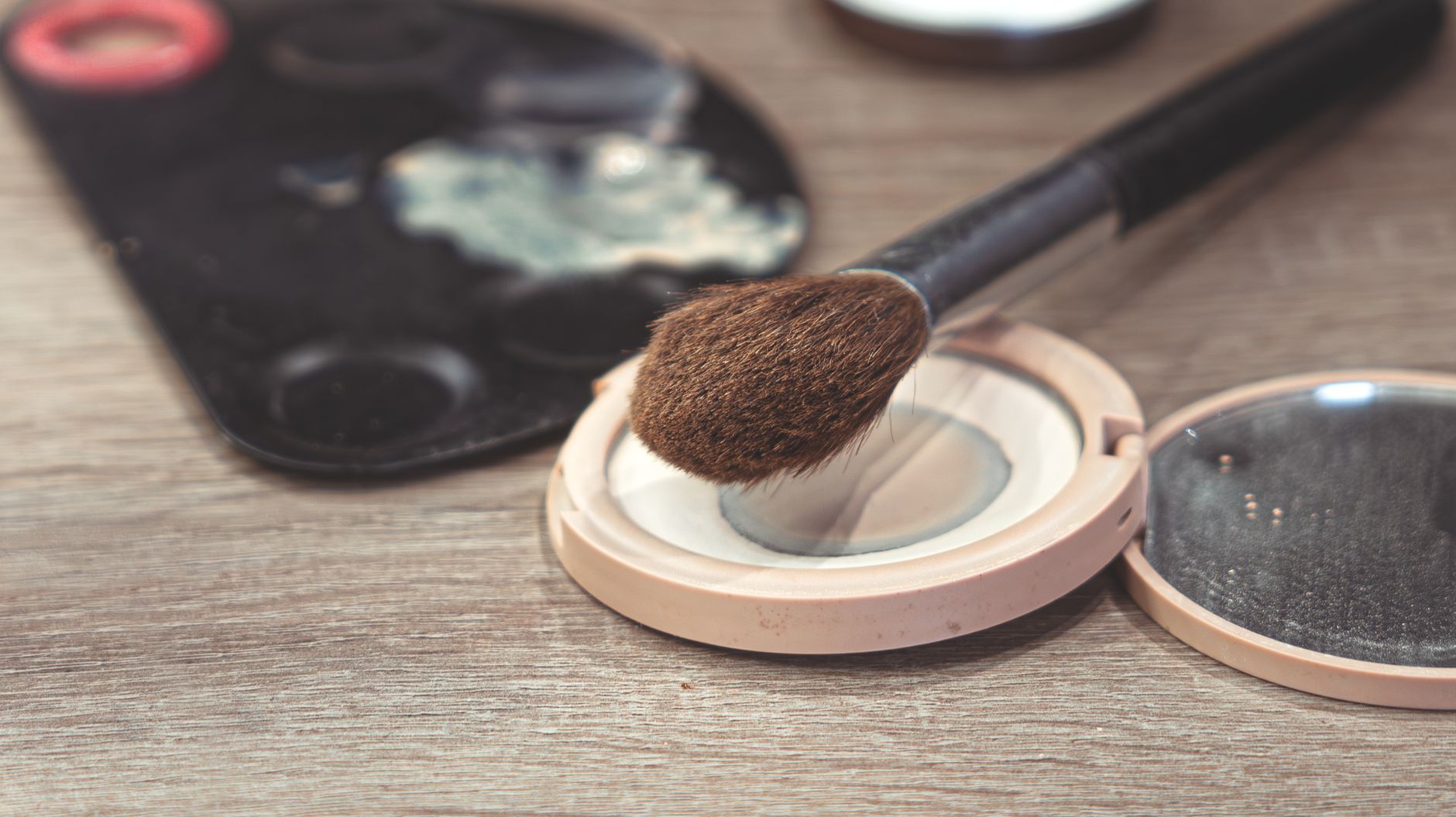 a selection of mineral makeup palettes featuring zinc oxide, mica, and iron oxides, arranged on a wooden vanity with soft daylight