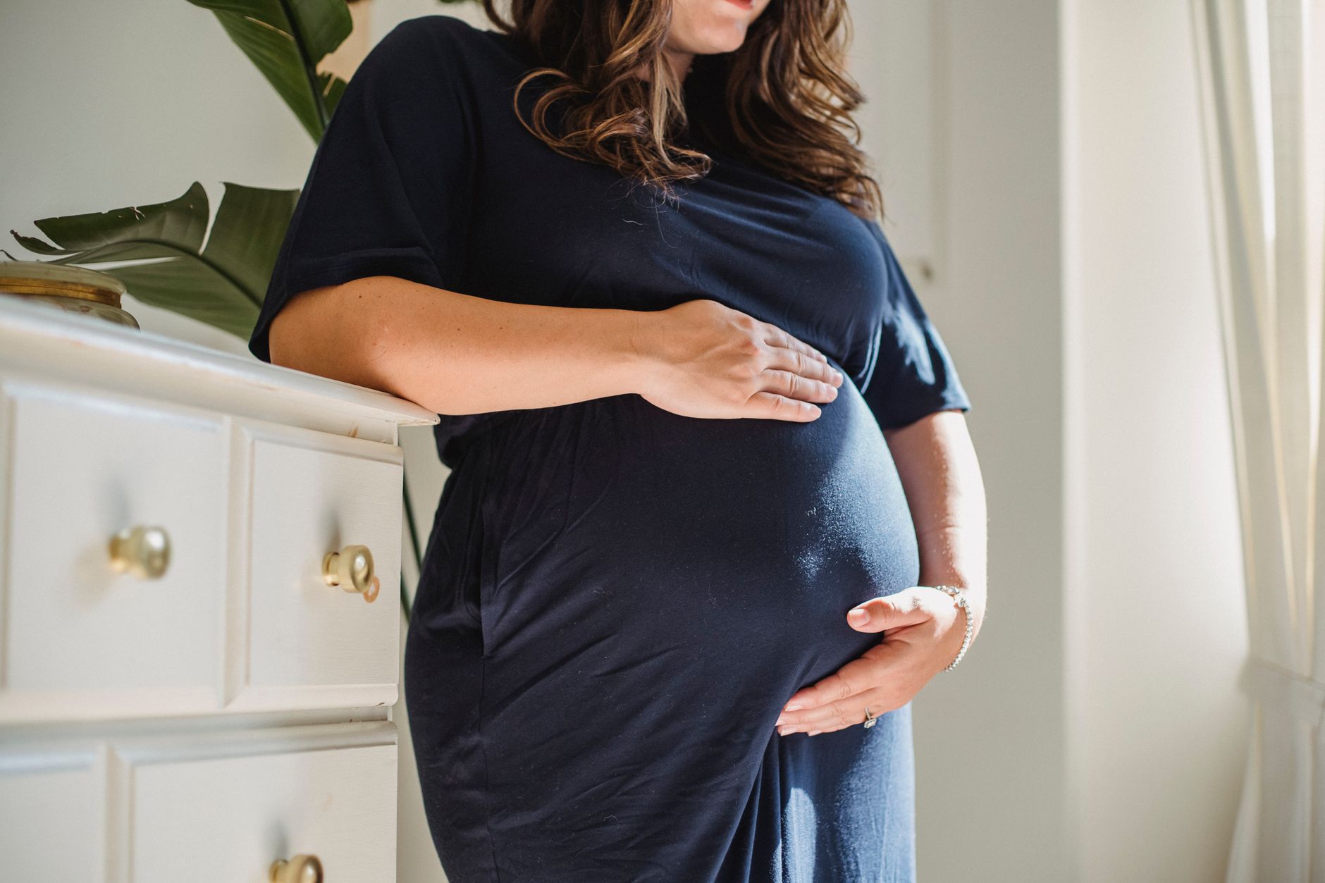 A close‑up of a hand applying a thin layer of Vicks Vaporub to a pregnant woman's chest, highlighting proper amount and location