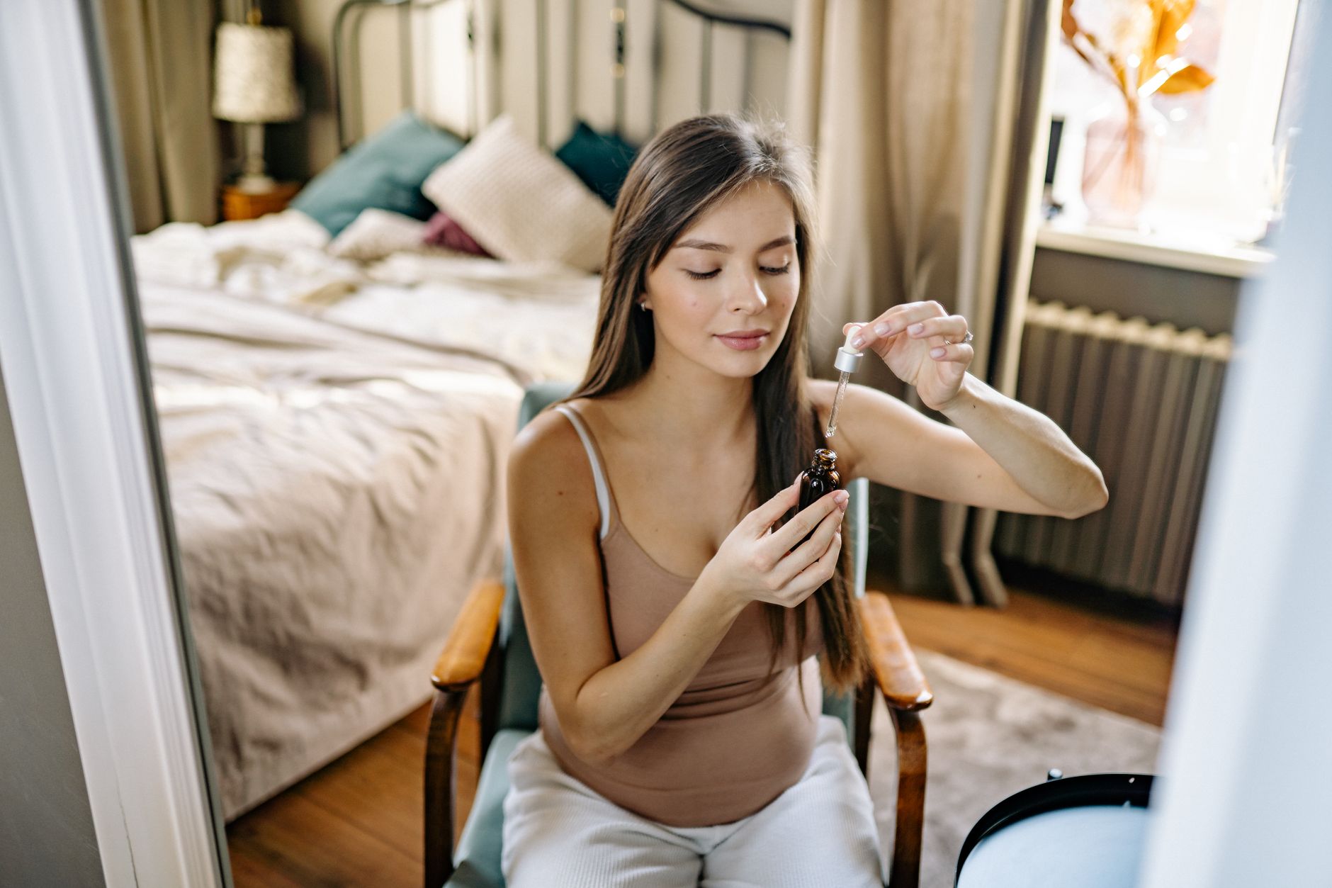 a pregnant woman gently applying a small amount of vitamin C serum to her forearm as part of a patch test, with a calm, home environment