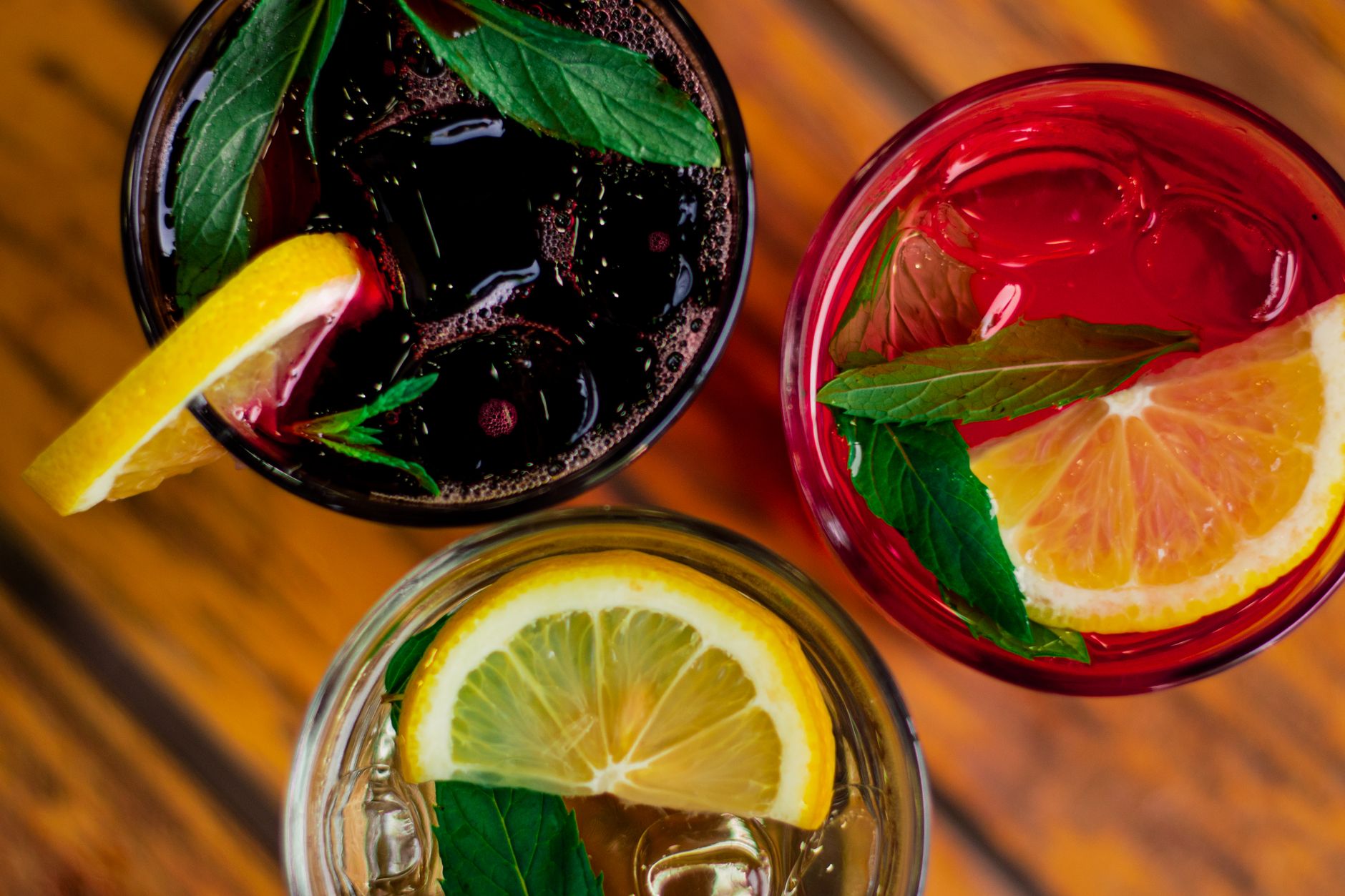 A variety of colorful non-alcoholic mocktails in elegant glasses, garnished with fruit and herbs, on a light background, no people