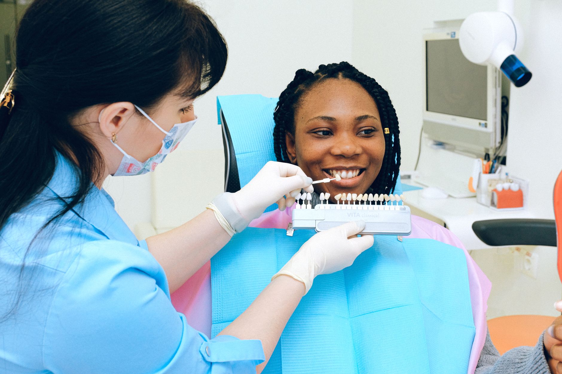 Close‑up of a dental professional’s hand holding a whitening strip while a pregnant patient watches, bright clinic lighting, focus on the product and calm atmosphere