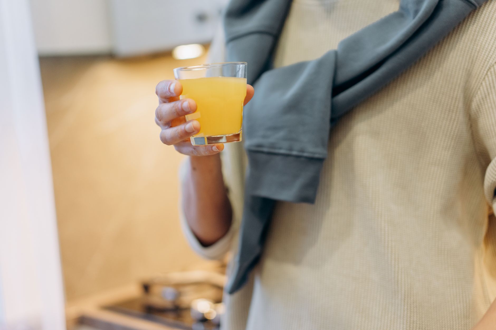 A pregnant person holding a plate of colorful vegetables and lean proteins, with a glass of fortified orange juice and a whole-grain tortilla in the background