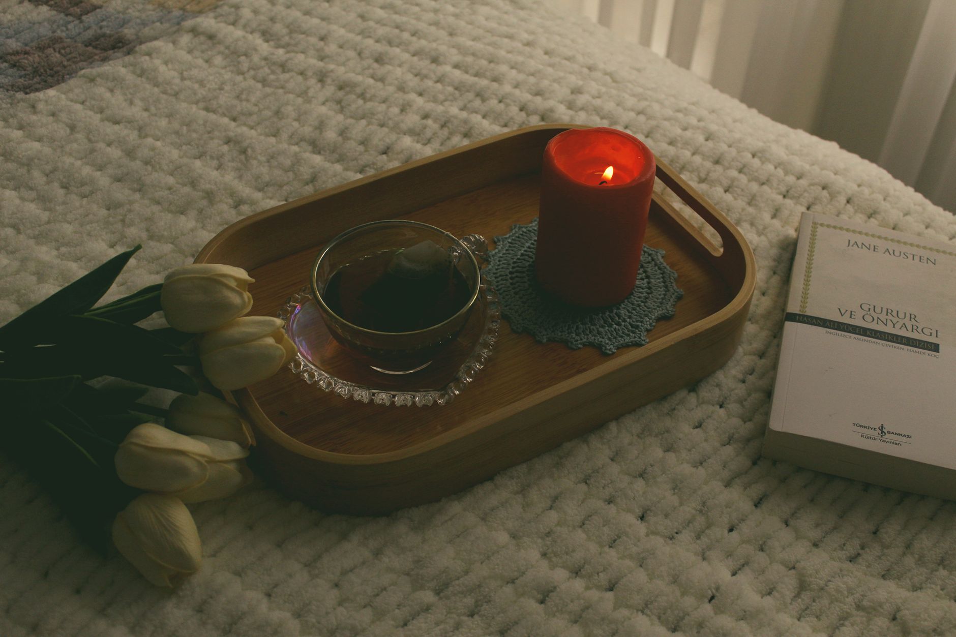 A cozy nightstand with a cup of herbal tea, a book, and a dim lamp, illustrating a calming bedtime routine for a pregnant person
