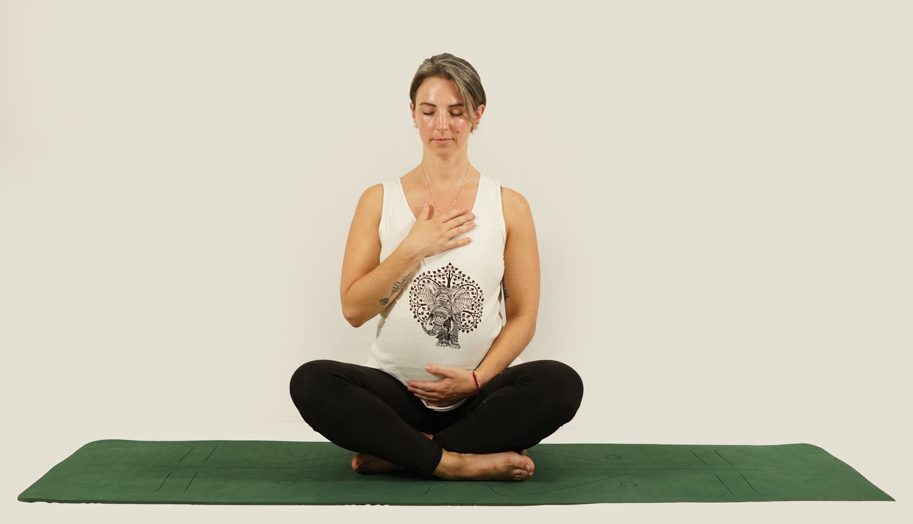 A pregnant woman practicing a gentle prenatal yoga pose outdoors on a mat, surrounded by lush green foliage, bathed in soft, natural light.