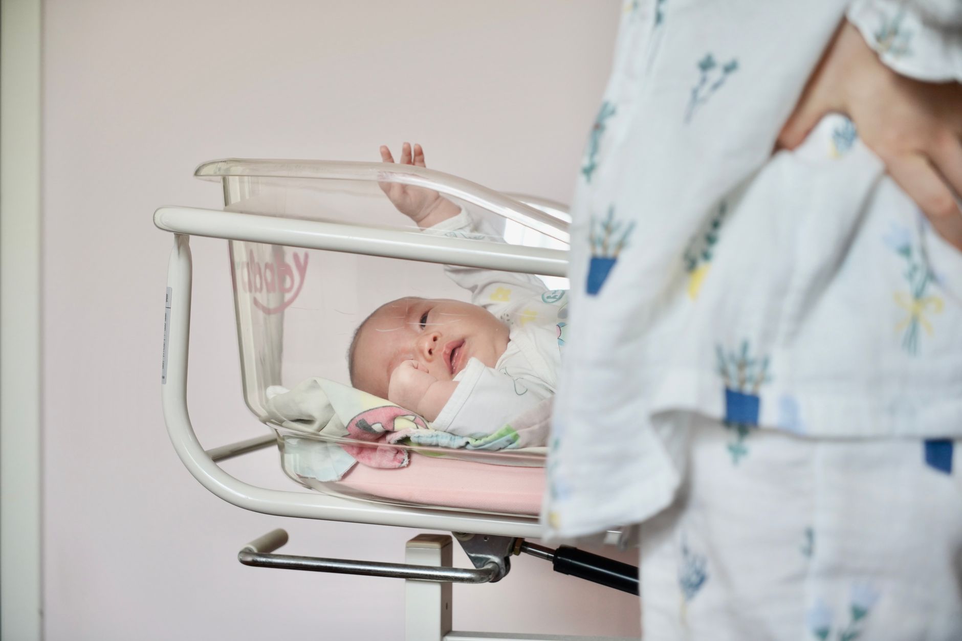 Overhead shot of a newborn baby in a hospital incubator receiving phototherapy, eyes covered with protective mask, blue light visible