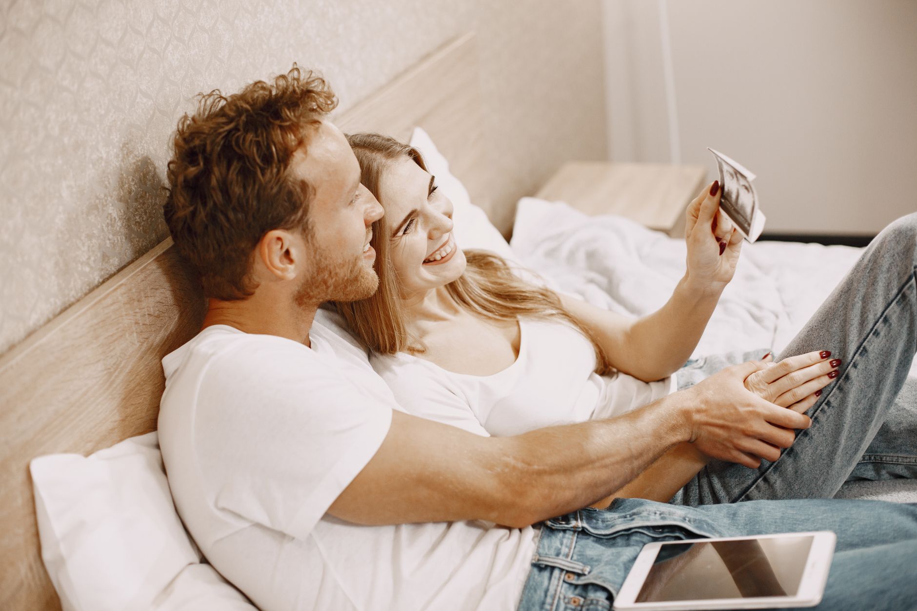 Couple holding hands, looking at an ultrasound scan.