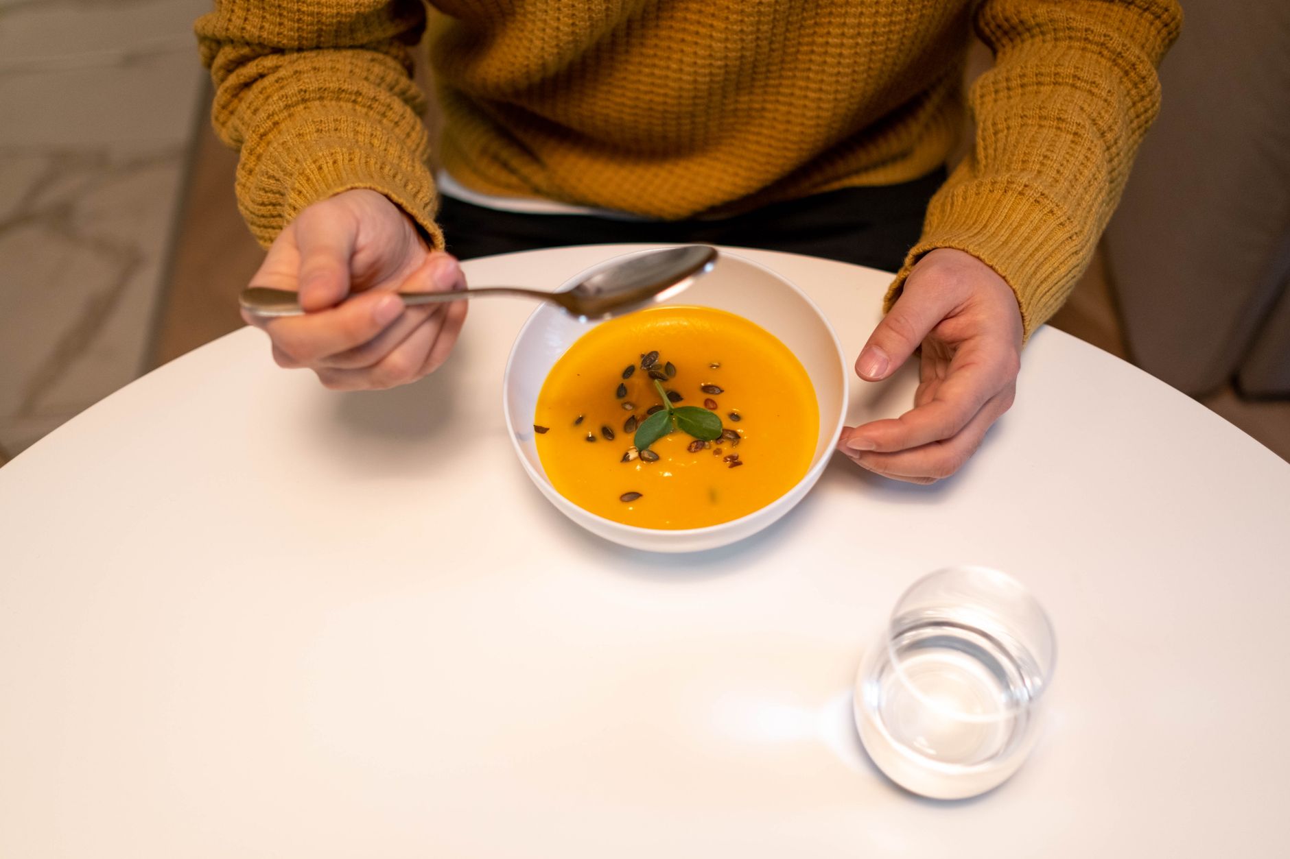 A postpartum mother resting with a bowl of soup and a glass of coconut water