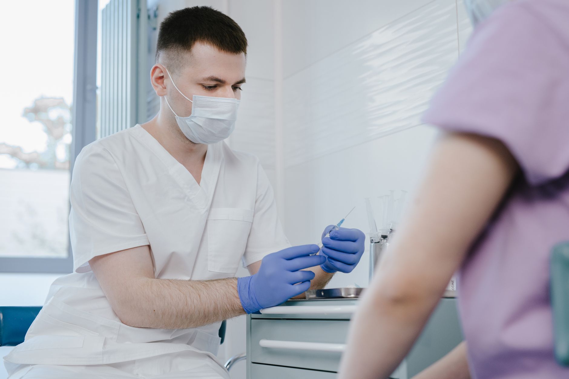 A healthcare provider gently administering a vaccine shot to a pregnant woman's arm, in a clean clinic setting. Only arms and upper torso visible, no faces.