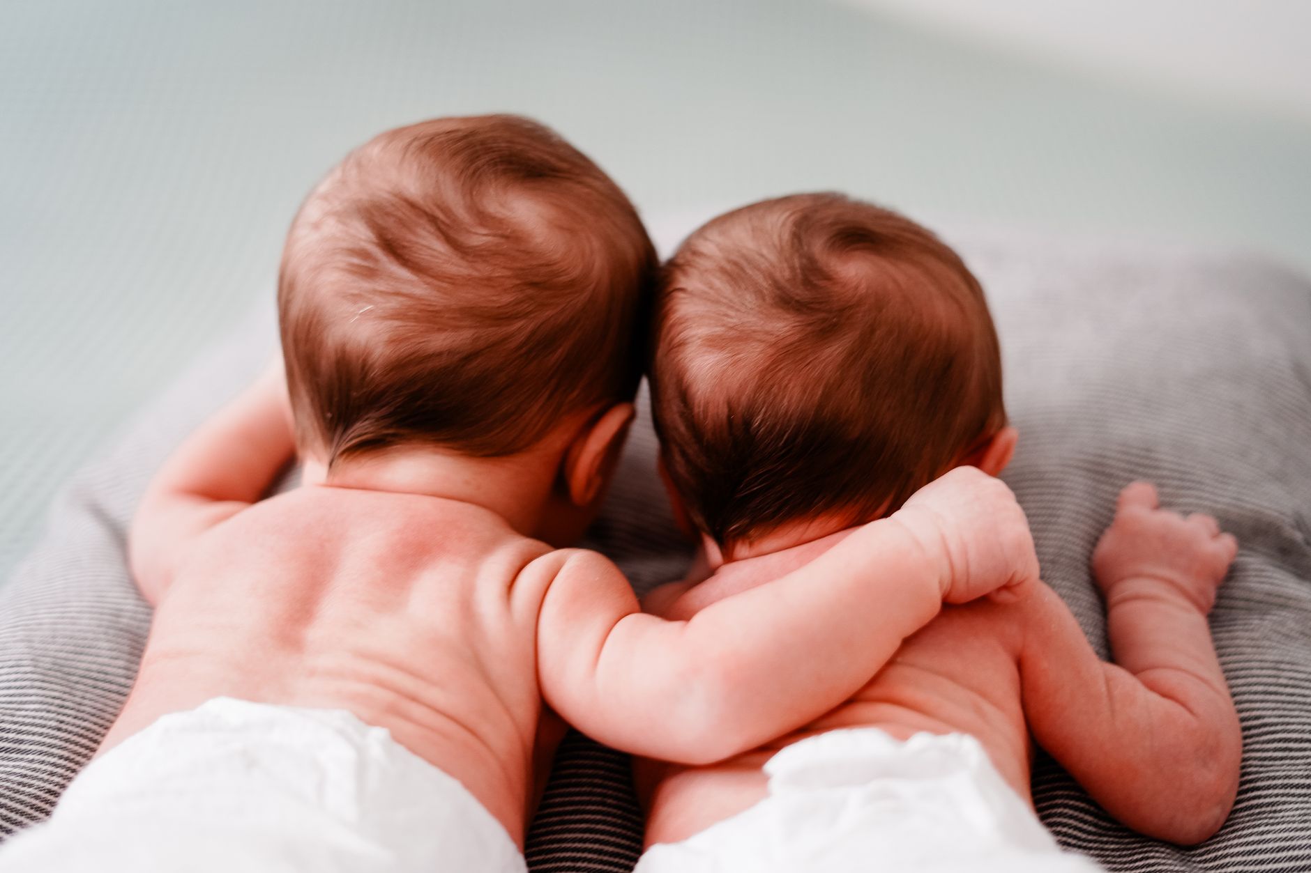 Two newborn twins being bottle‑fed on a bedside table with soft night‑light and a prepared feeding kit