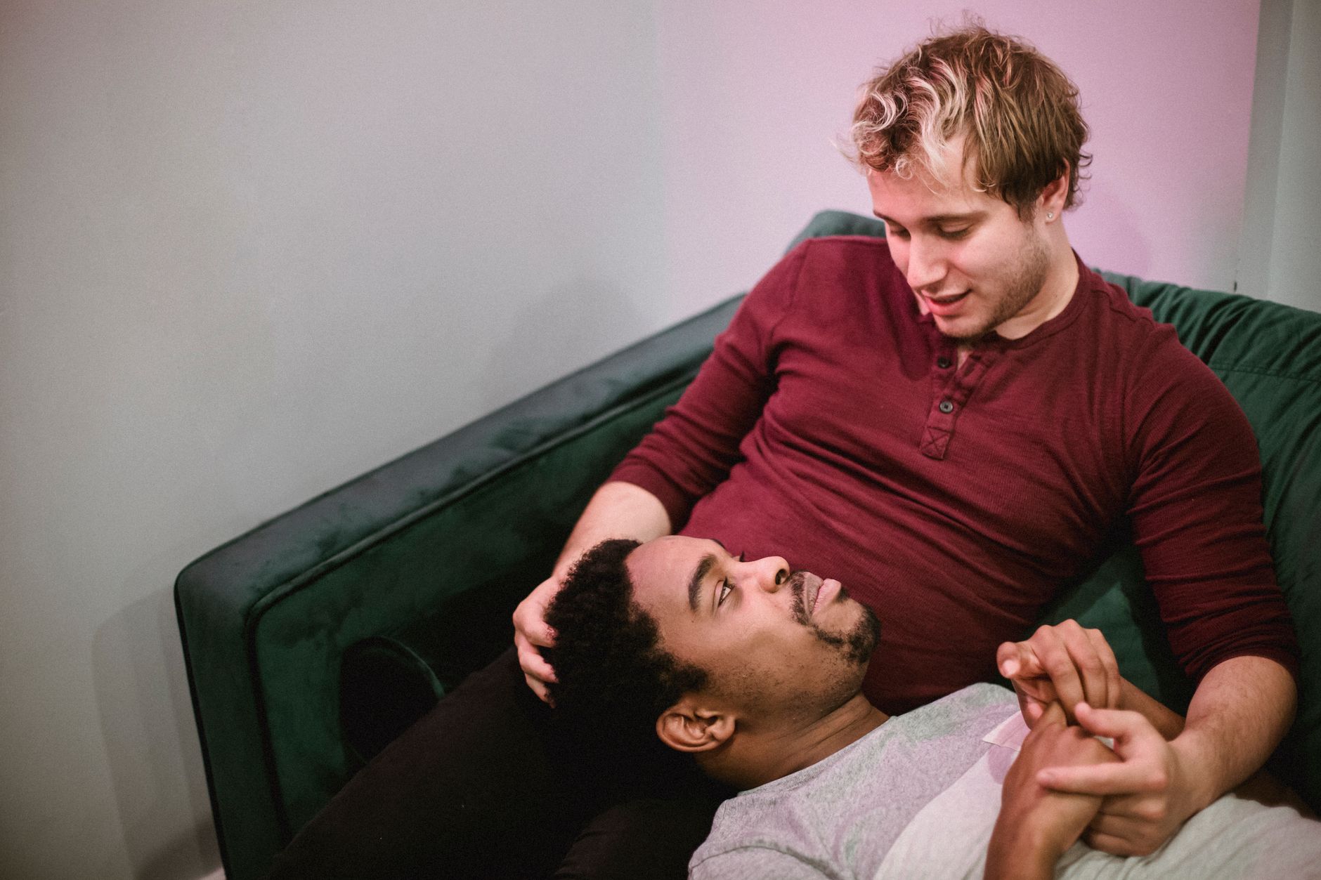 Two parents sitting on a couch, holding hands and looking at each other with warm expressions