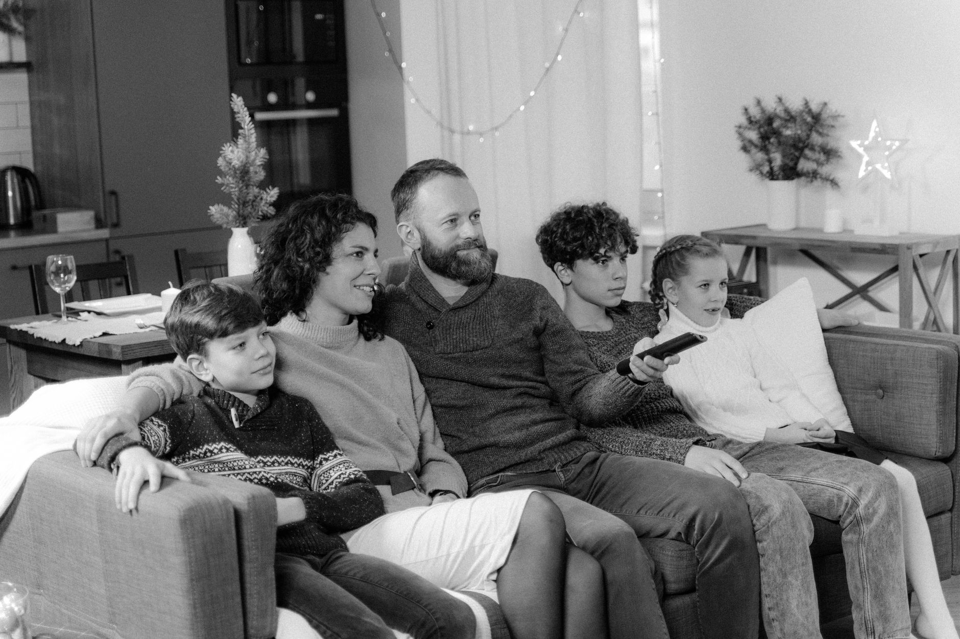 A couple sitting on a couch with their two children watching TV