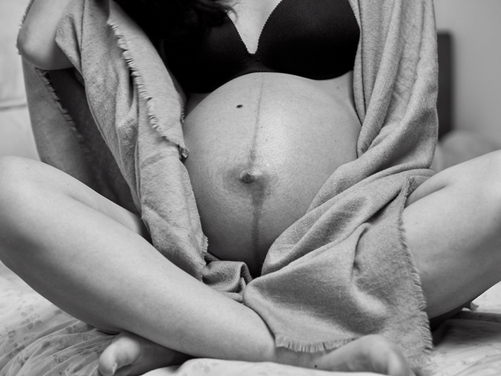 A close-up of a pregnant woman's belly showing a subtle linea nigra, with soft focus on the surrounding skin, natural light