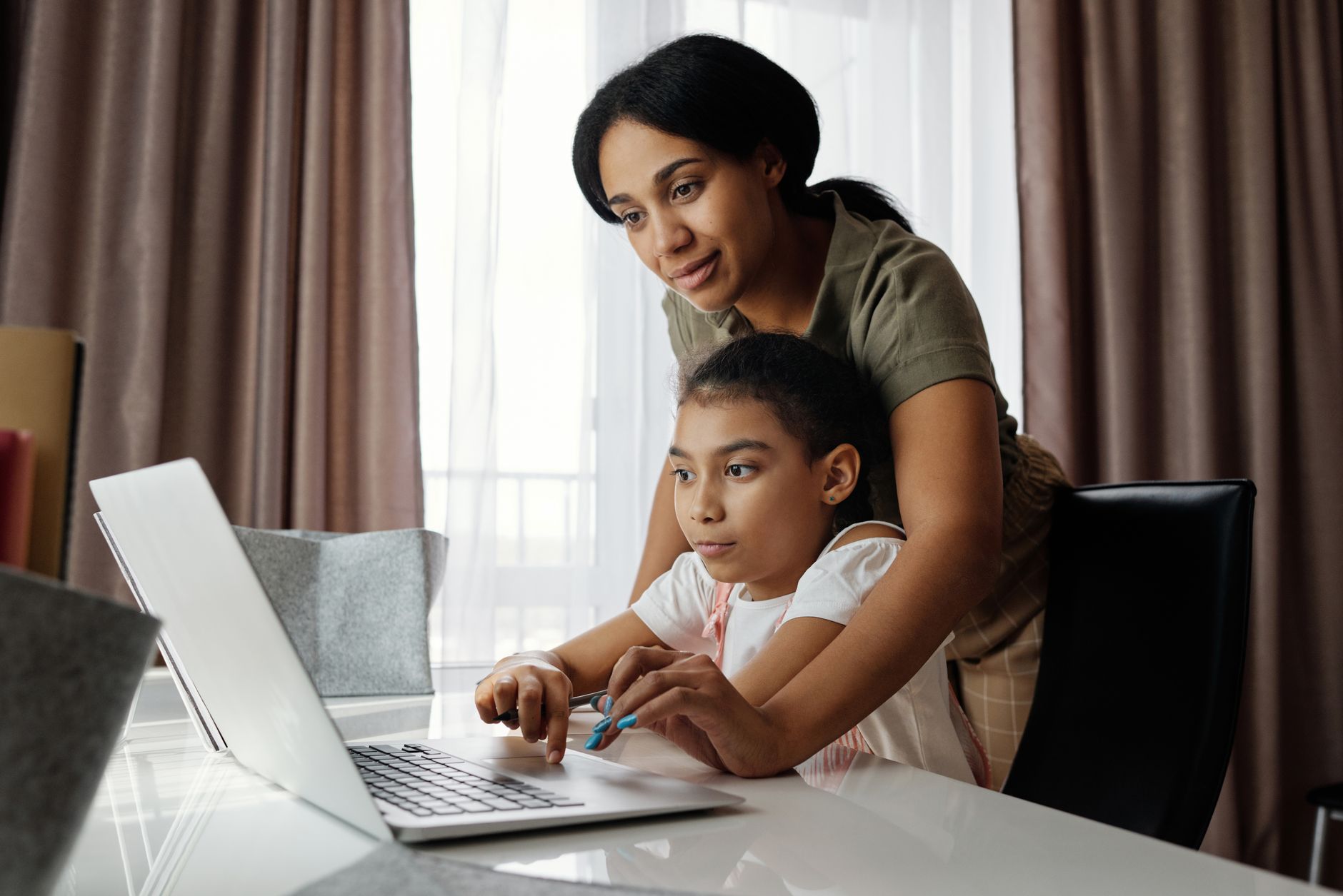 A military spouse mother helping her child with homework at a kitchen table.