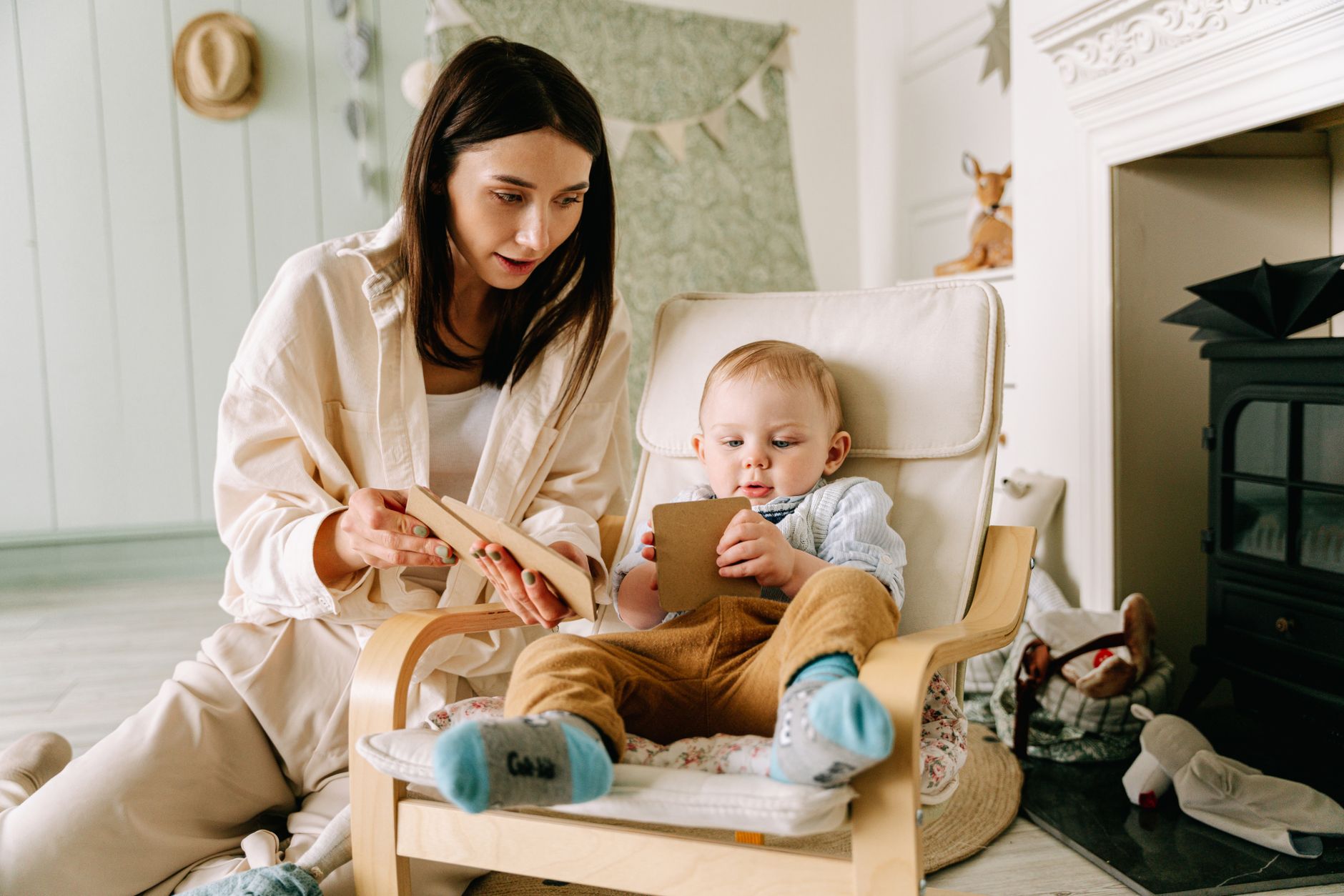 A mom sitting on the floor with her eyes closed, taking a deep breath while her toddler plays nearby