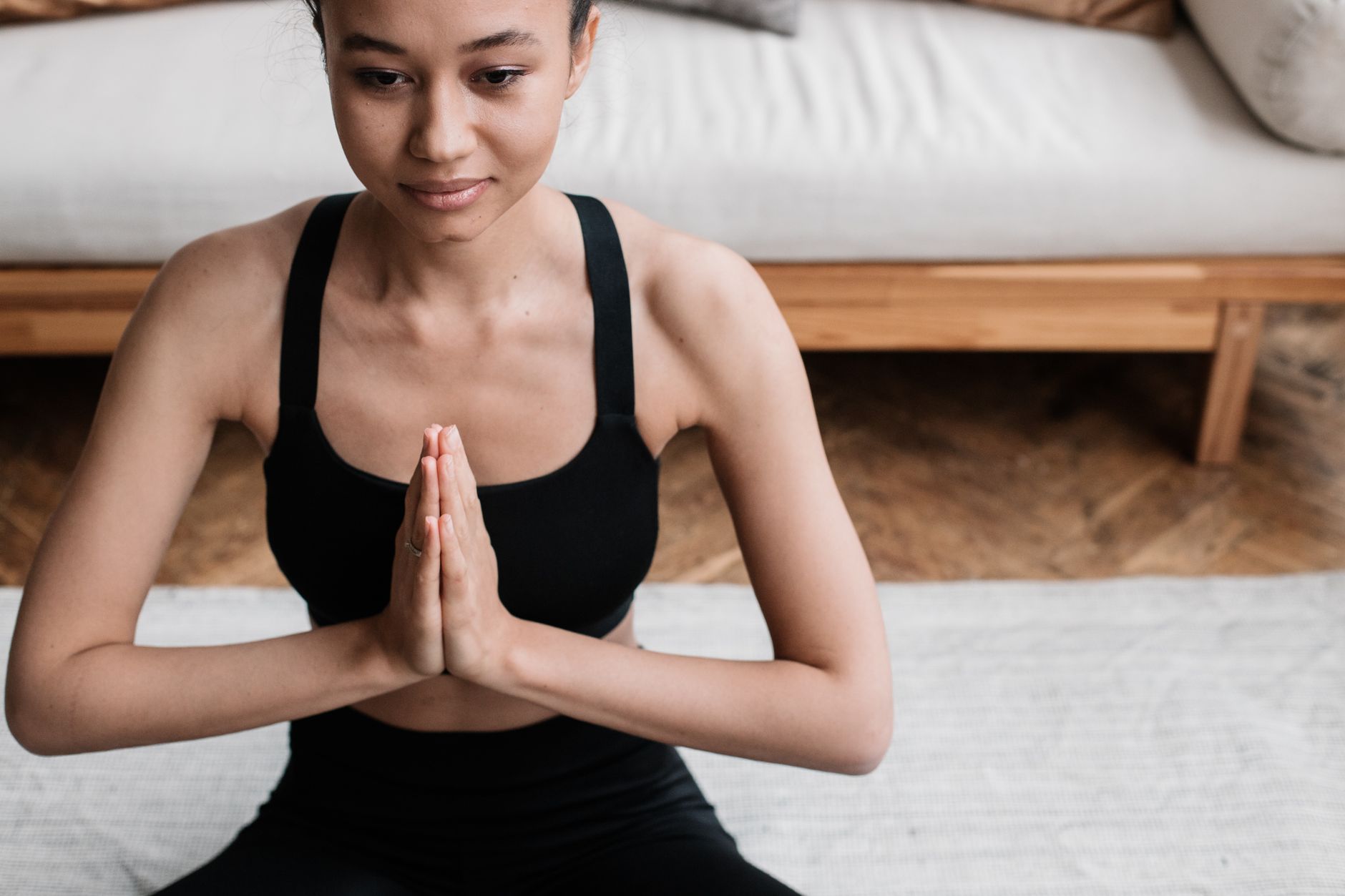 A serene woman meditating or practicing mindfulness in a calm, tidy home environment, suggesting self-care and stress management.