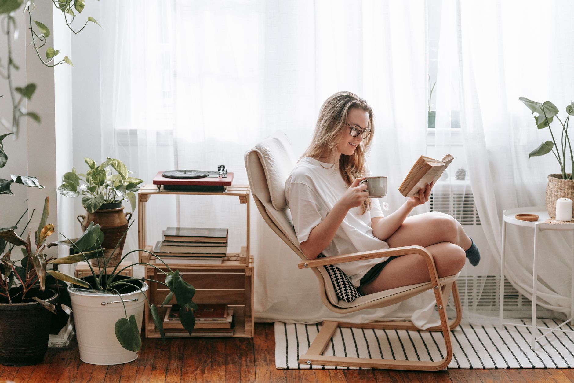 A third-trimester mom lounging with a postpartum recovery kit, a book, and a cup of tea.