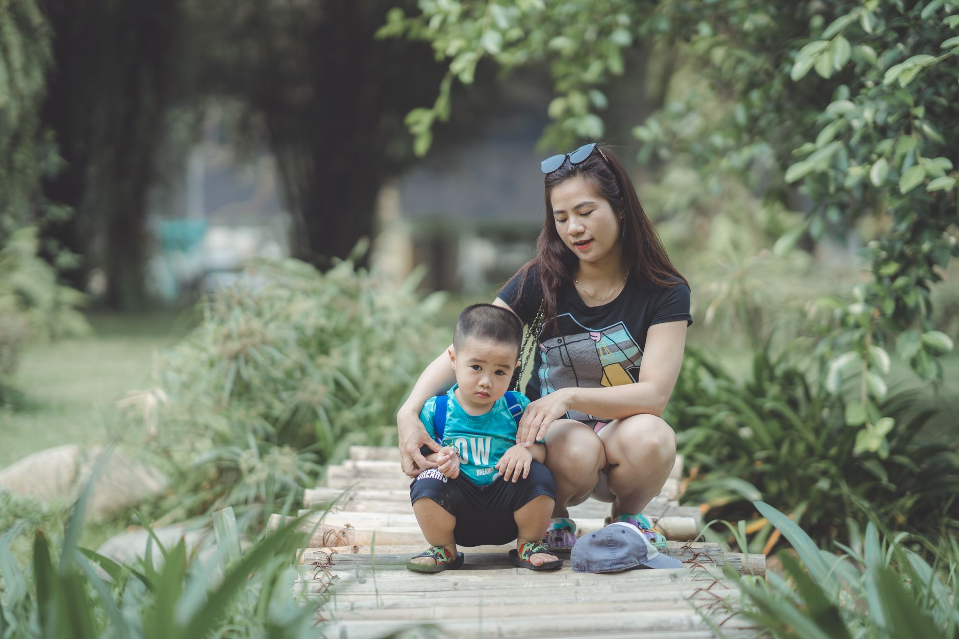 A mom sitting on a couch with her baby, looking thoughtful, while her partner sits nearby with a reassuring expression