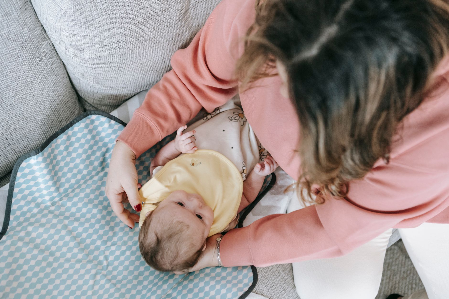A nanny gently holding a sleeping newborn while organizing baby bottles on a counter