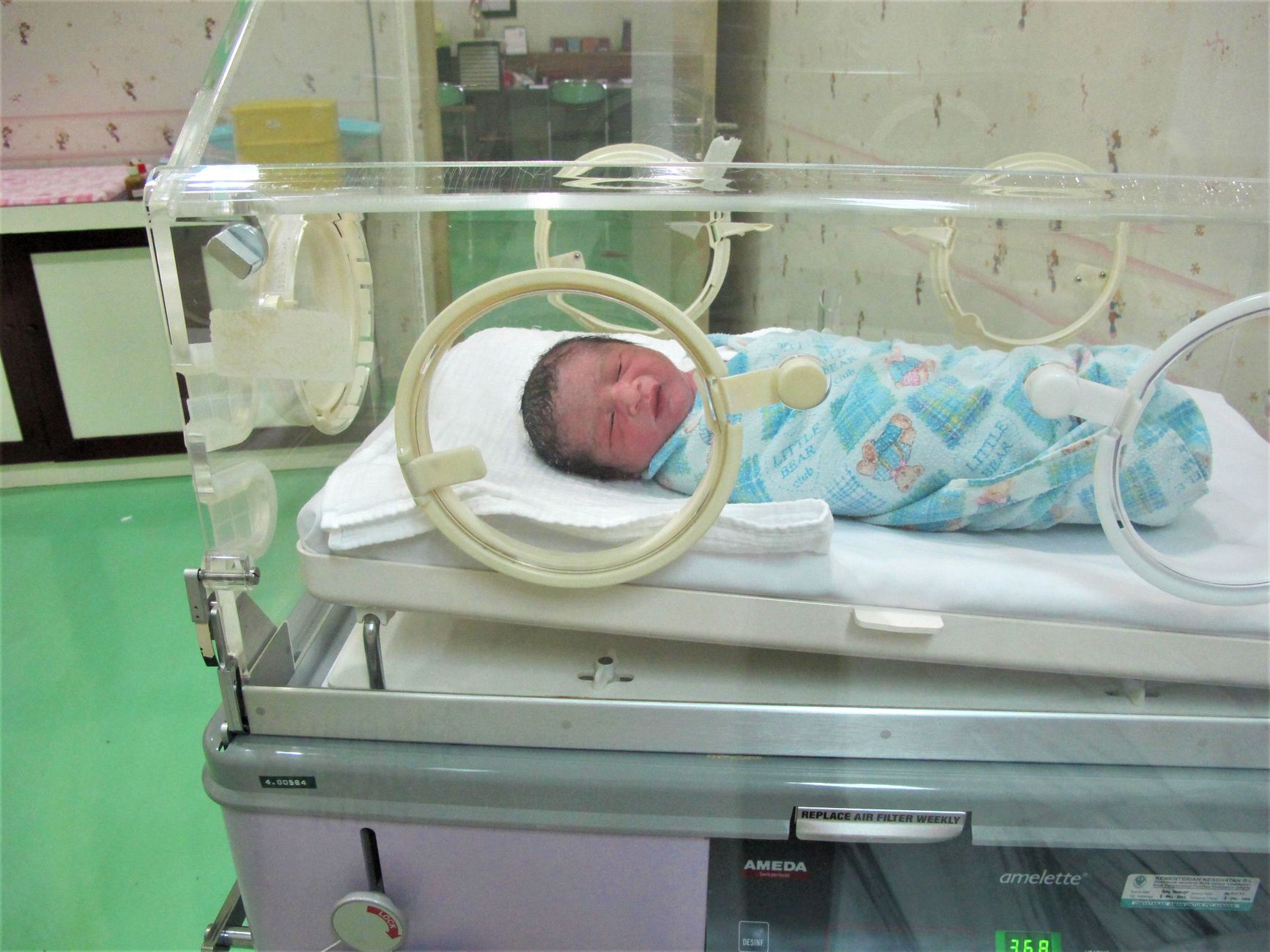 A neonatal intensive care unit with a baby under a warm incubator, CPAP machine tubing visible, soft ambient lighting, clean clinical setting