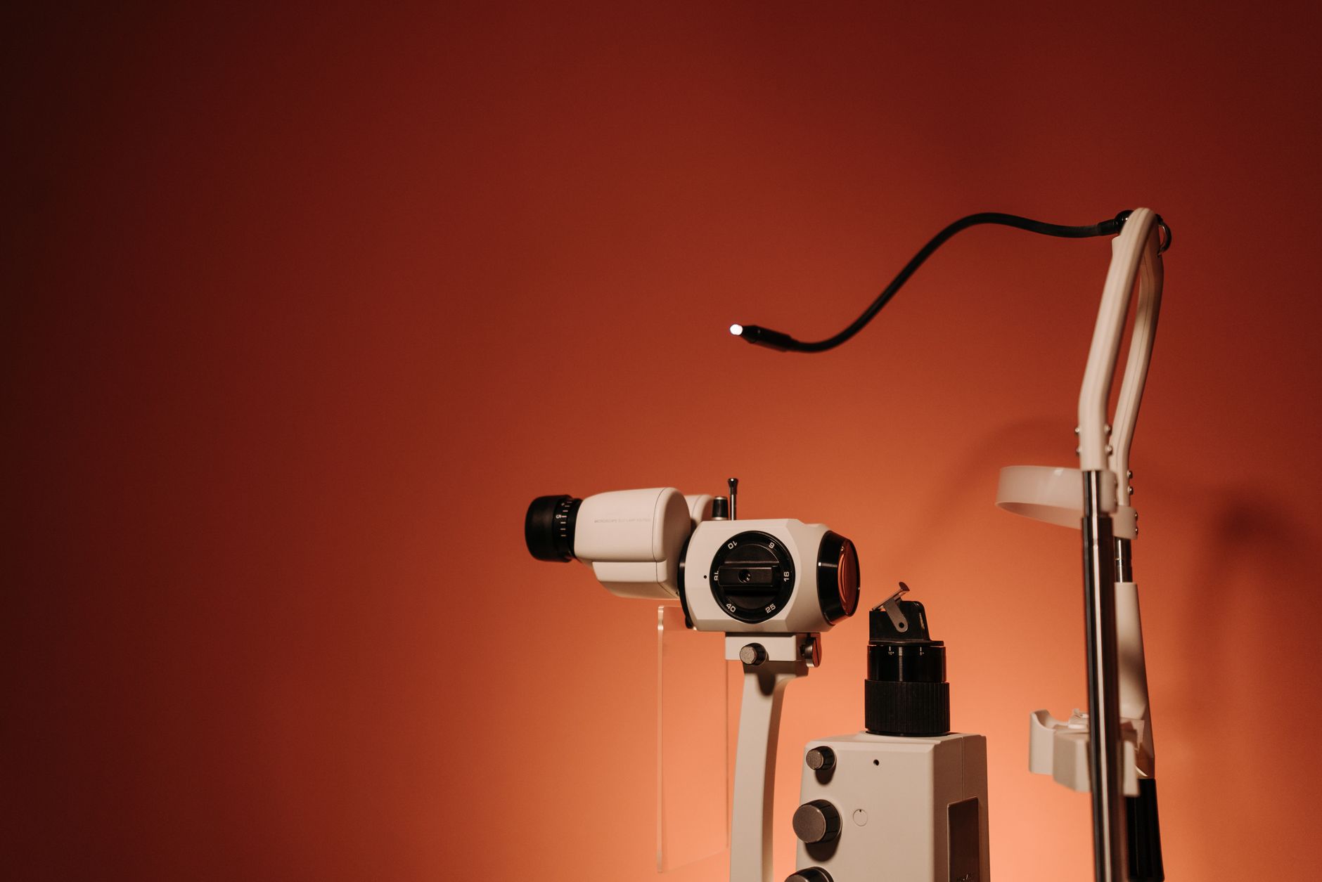 Pediatric ophthalmologist gently examining a toddler's eye with a handheld slit‑lamp in a softly lit clinic