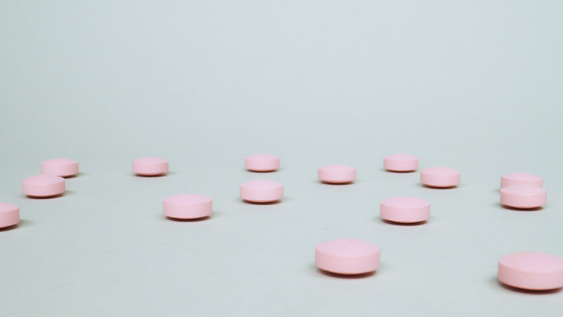 A small dropper of probiotic supplement beside a glass of breast milk on a pastel kitchen counter, bright morning light