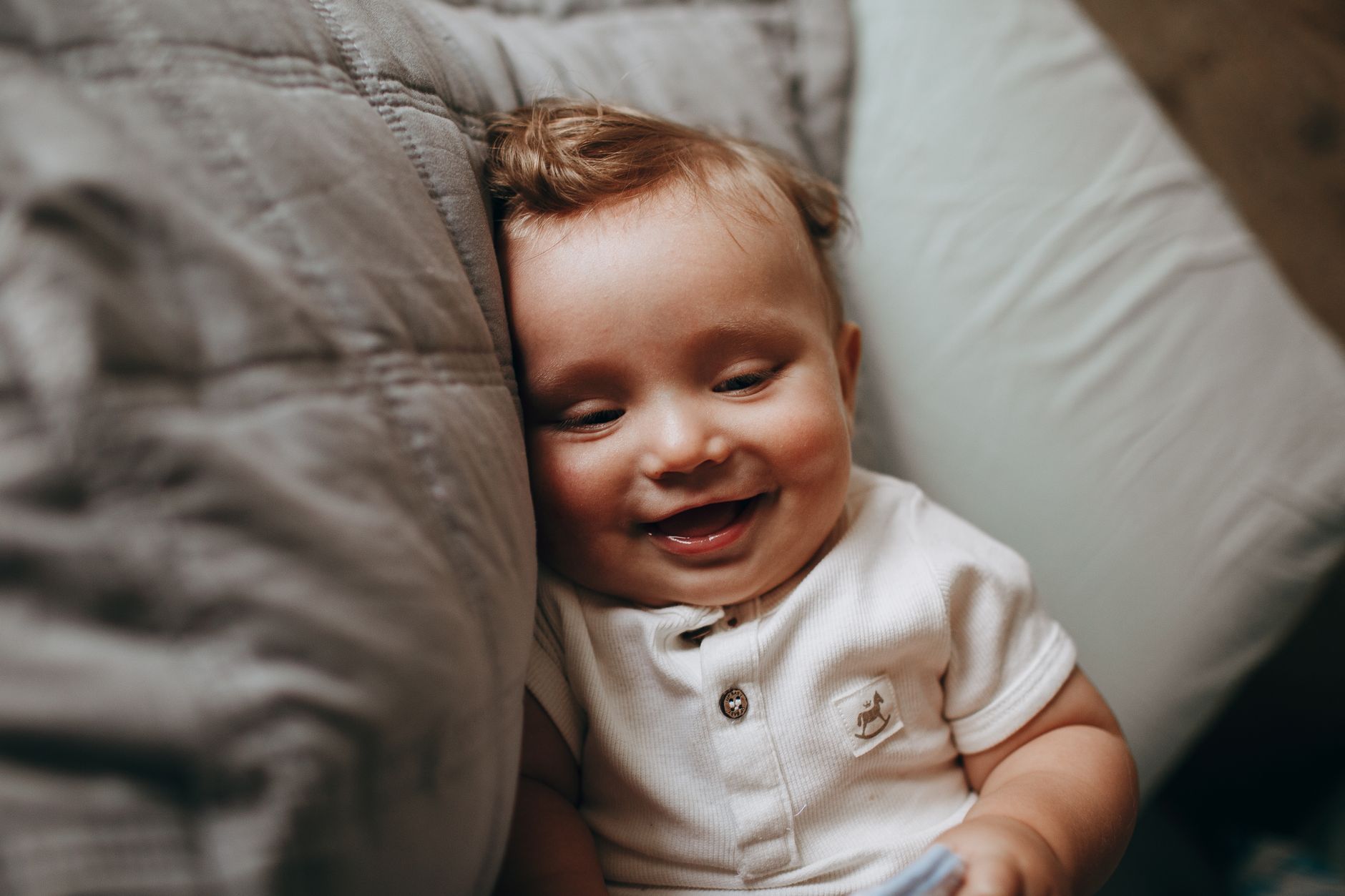 Four‑week‑old baby smiling at a parent, soft natural light highlighting the baby's bright eyes and gentle grin