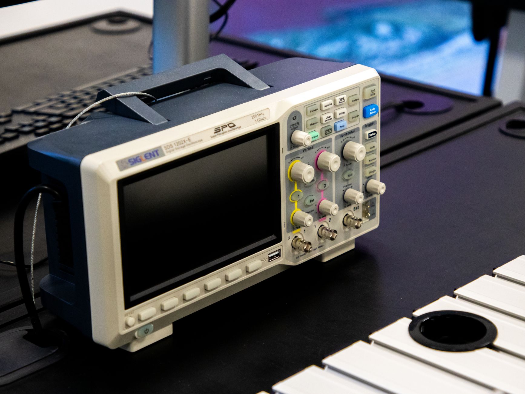 A close‑up of a neonatal monitor displaying a waveform, with a researcher’s hand holding a tablet showing a pain‑analysis algorithm, soft ambient lighting suggesting a research lab
