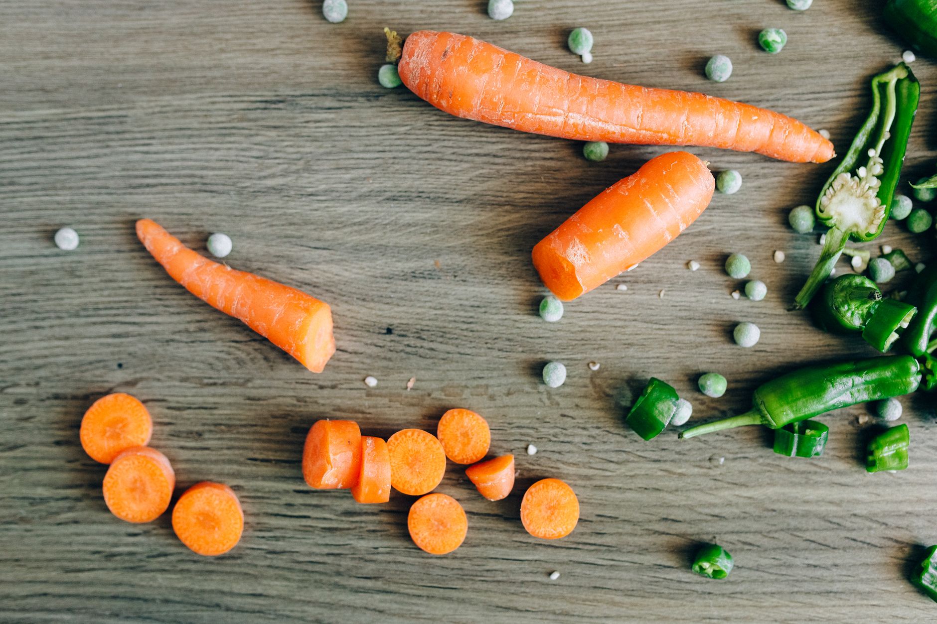 Close‑up of a baby’s high‑chair tray with small piles of pureed carrots, peas, and banana, bright natural light emphasizing the colors