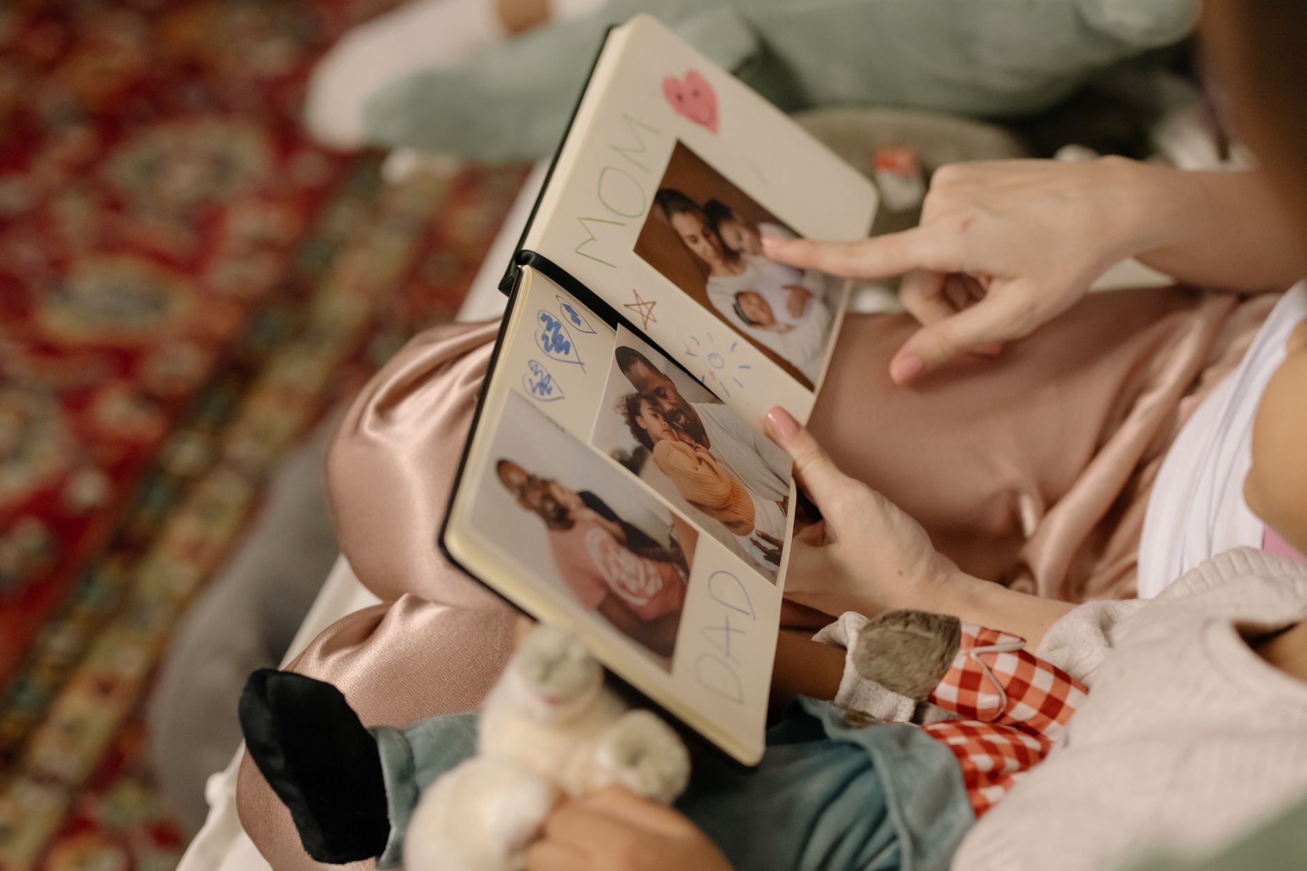 A parent and child sitting together, gently flipping through a photo album of their baby who passed away in the NICU.