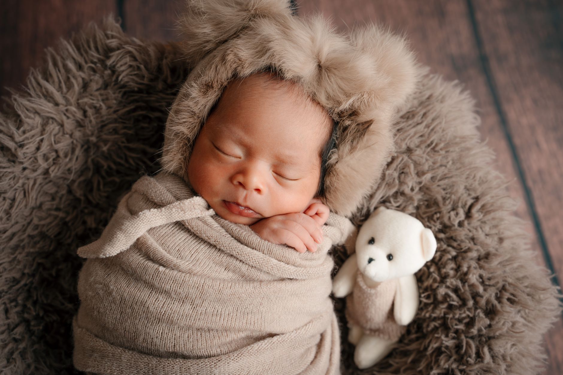A cozy nursery corner with a soft blanket, a plush teddy bear, a low‑light lamp, and a baby swaddled in a gentle wrap, bathed in warm morning light