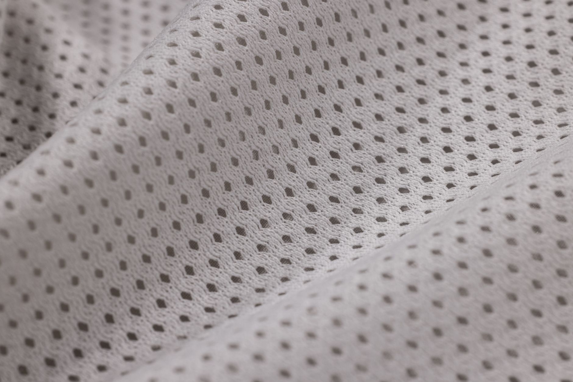 A calm newborn lying on a breathable bamboo mesh mattress, with a light cotton sleep sack and a digital thermometer nearby