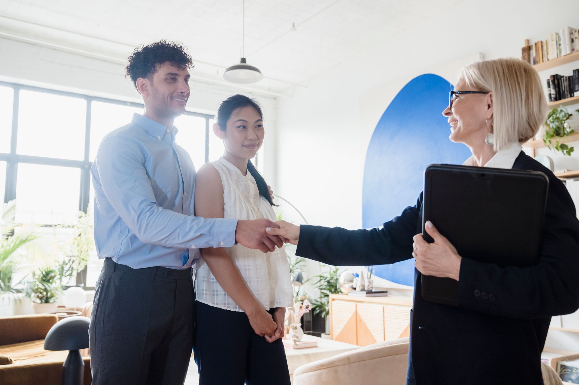 A professional woman smiling and shaking hands with an HR representative in a modern office, signifying a successful negotiation or discussion.