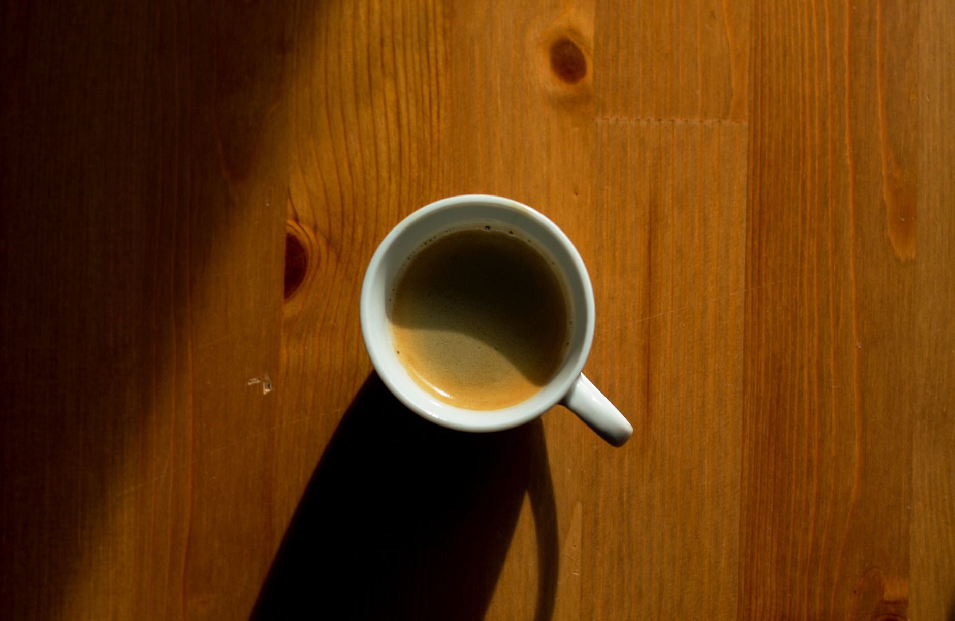Toddler sitting on a soft blanket with a small cup of clear oral rehydration solution, sunlight streaming through a kitchen window