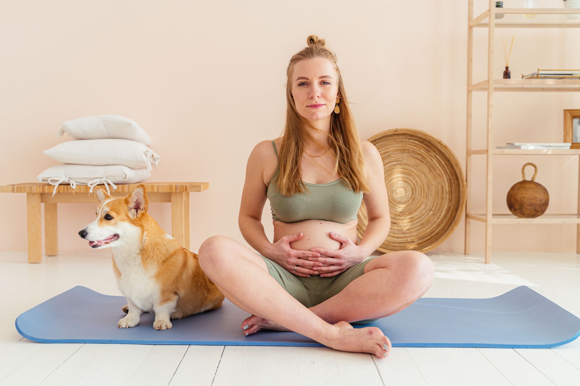 Pregnant woman practicing gentle meditation or mindfulness, sitting comfortably with hands on belly, serene expression, soft light