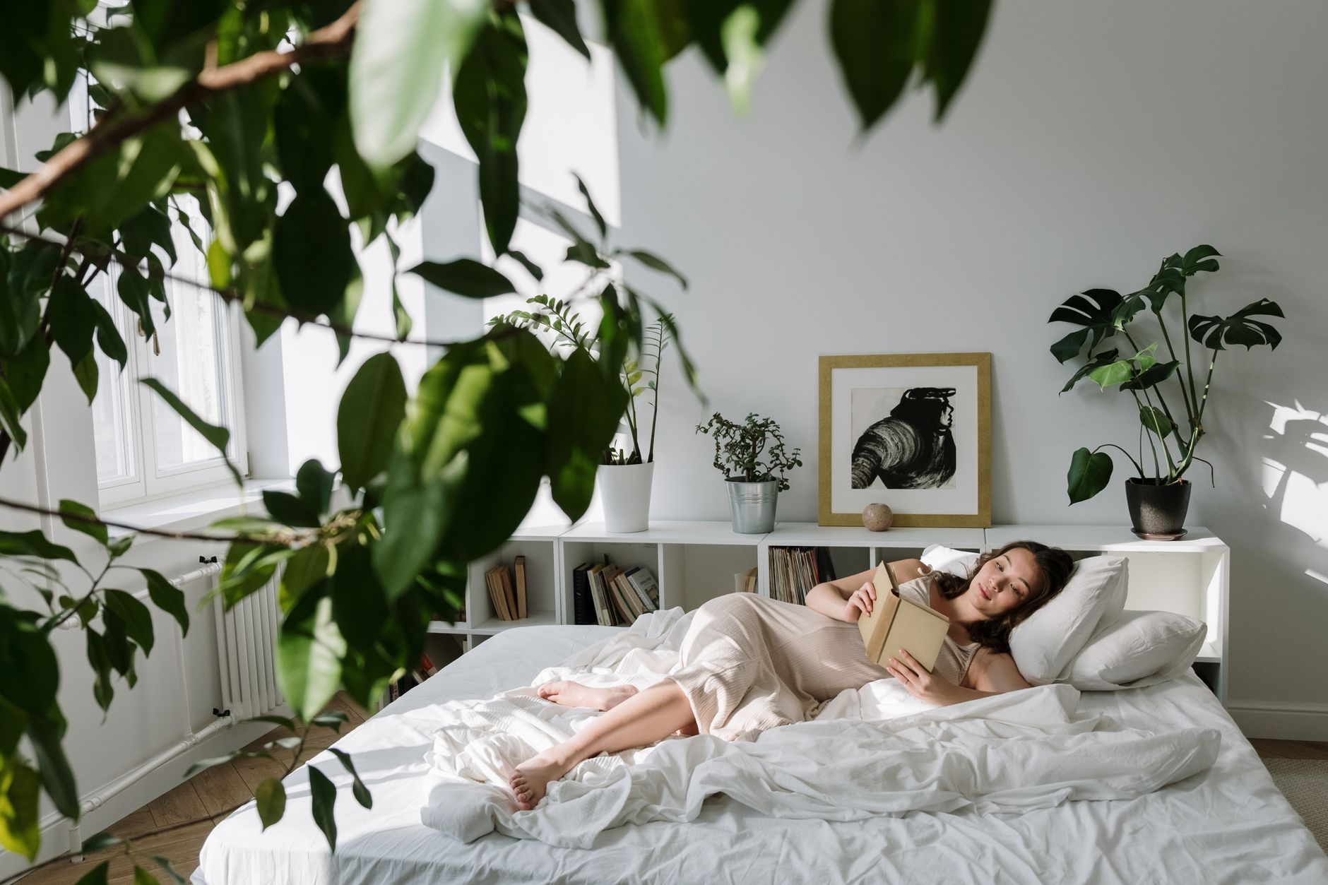 A warm, inviting bedroom scene with a pregnant woman resting peacefully on a bed, natural light filtering in, soft blankets, and a book nearby