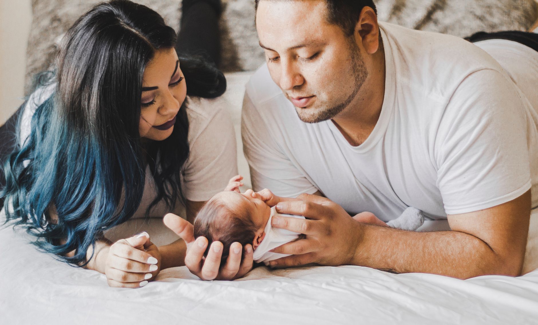 A mother holding her baby while a partner watches supportively