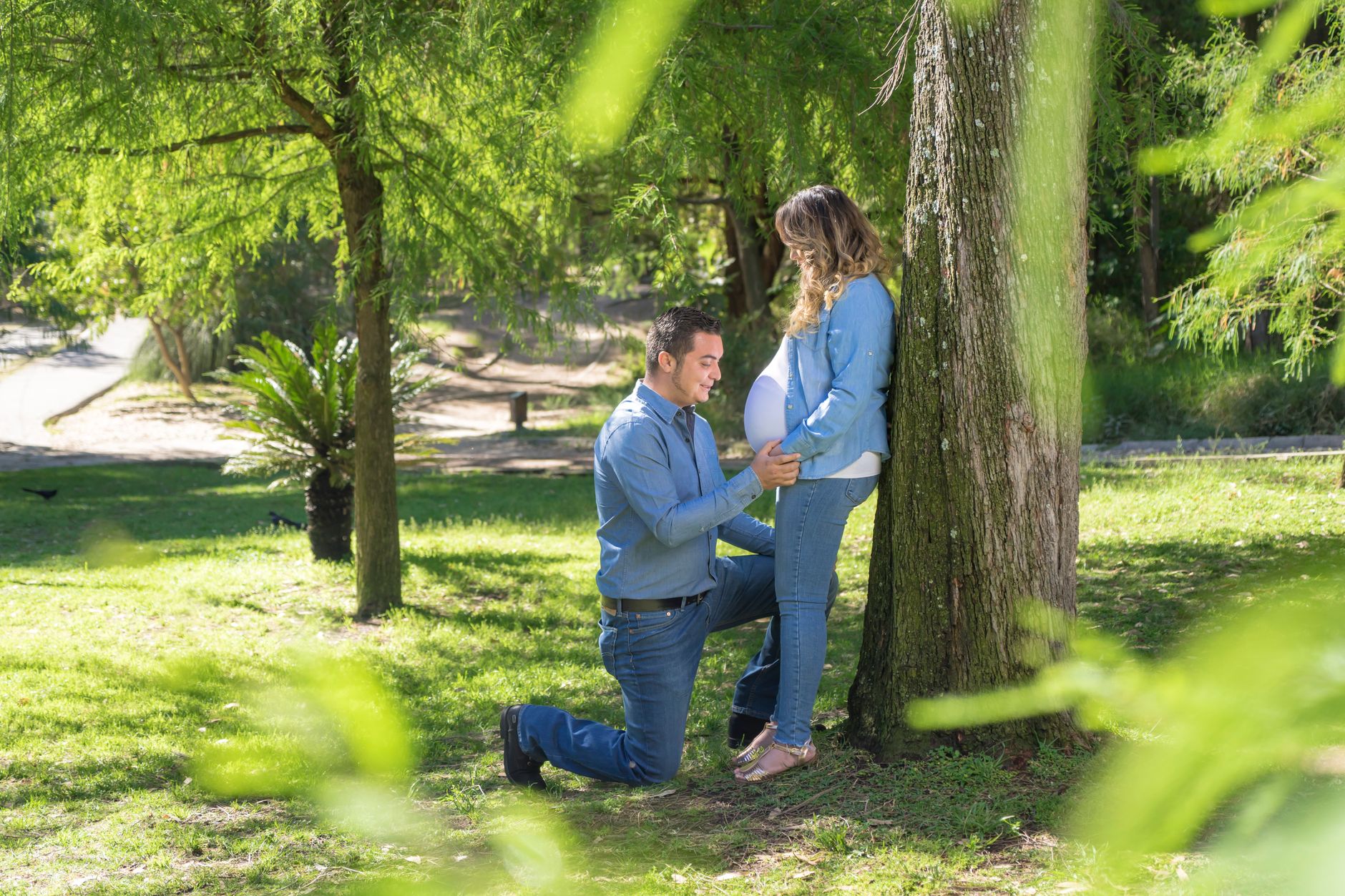Pregnant woman wearing supportive maternity belt while strolling in a park, soft daylight highlighting her relaxed posture