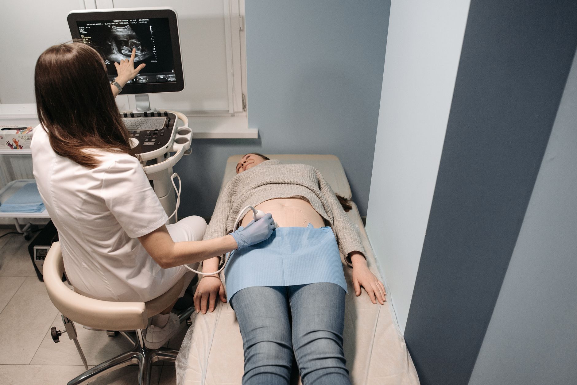 Second trimester prenatal check-up, mother seated with doctor reviewing ultrasound images, bright clinic lighting