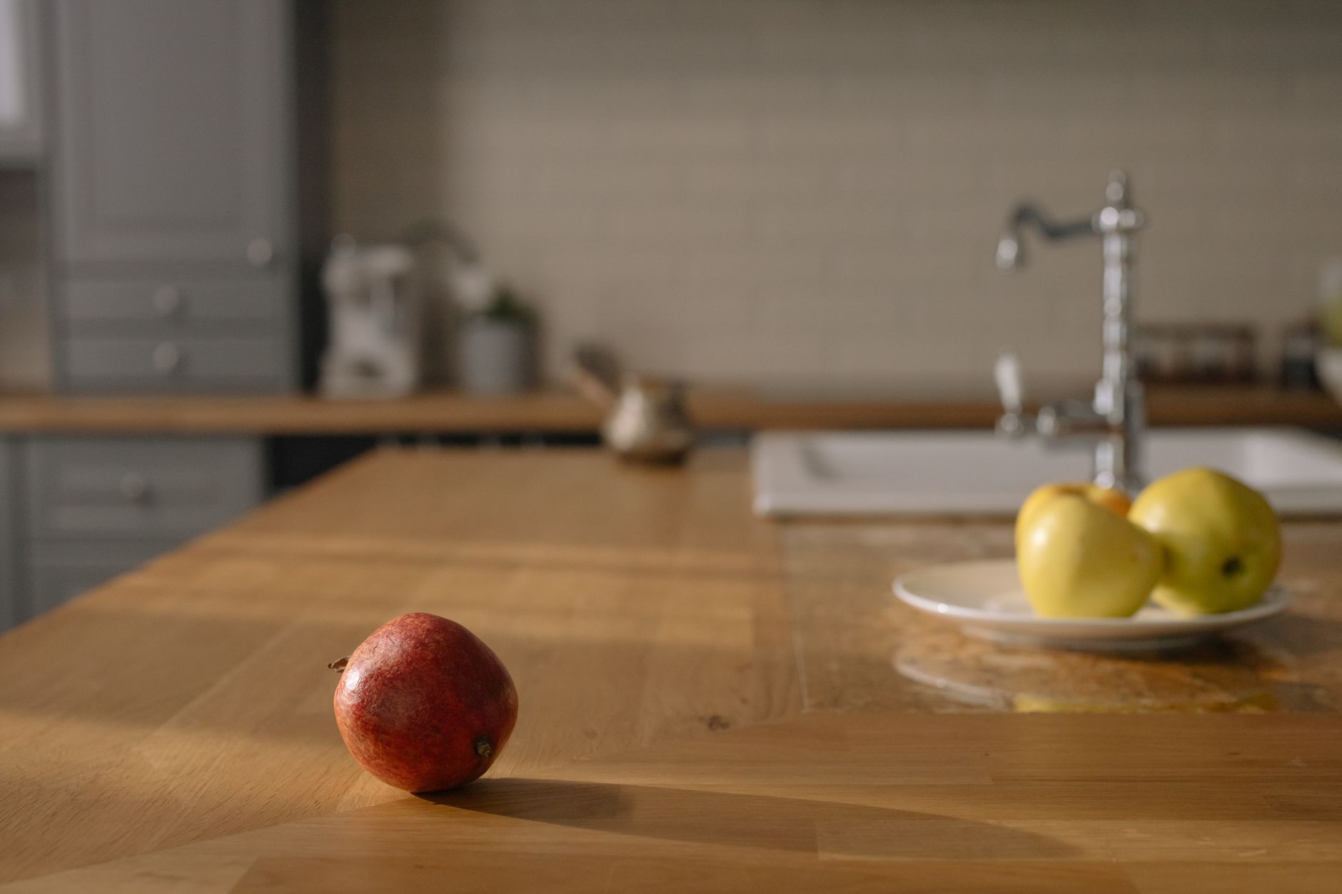 Pregnant woman sipping water from a glass pitcher on a sunny kitchen counter, surrounded by fresh fruits and a notebook, warm natural light, photorealistic