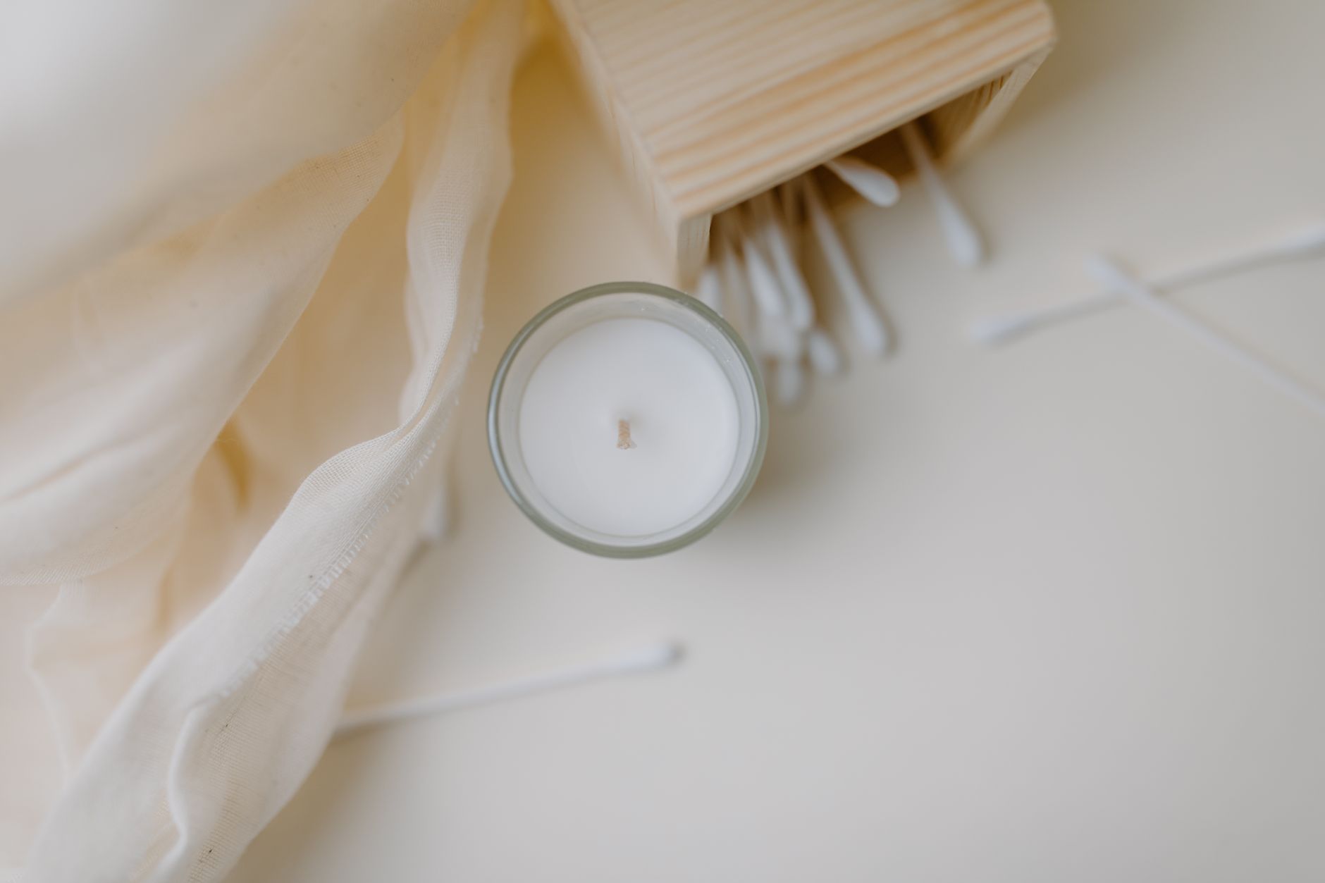 A close‑up of a soft, breathable cotton pillow cover with a subtle pattern, laid on a wooden nightstand next to a lavender-scented candle