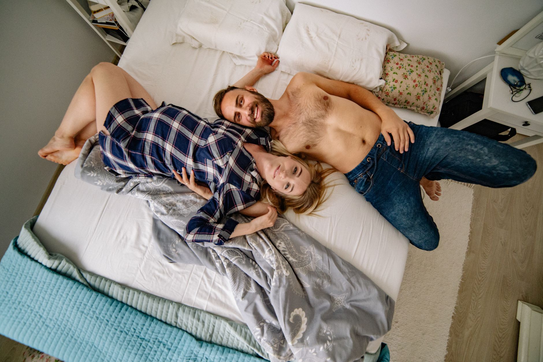 Pregnant couple in a side‑lying position with pillows, soft bedroom lighting, showing comfort in the third trimester