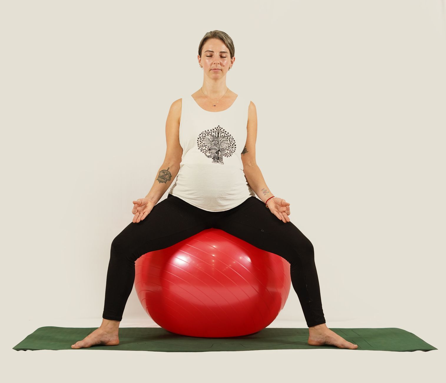 A pregnant woman in a softly lit studio practicing gentle prenatal yoga on a mat, with a yoga block and a water bottle nearby