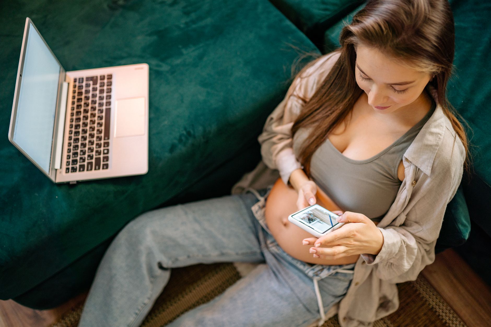 Woman holding a smartphone displaying a heart‑rate graph while sitting on a cozy sofa, soft natural light