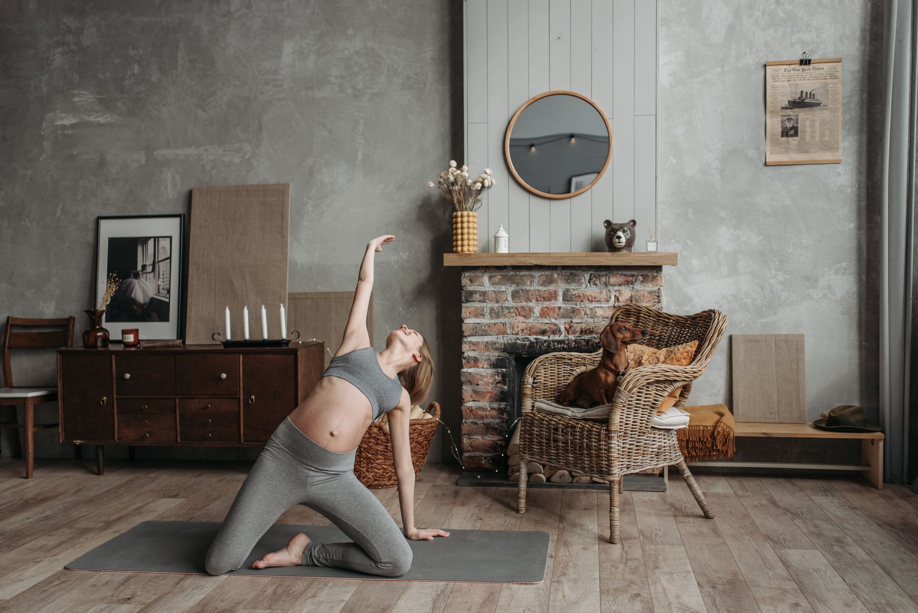 Pregnant woman in a bright kitchen doing a gentle stretch with a yoga mat, sunlight streaming through a window, soft pastel decor