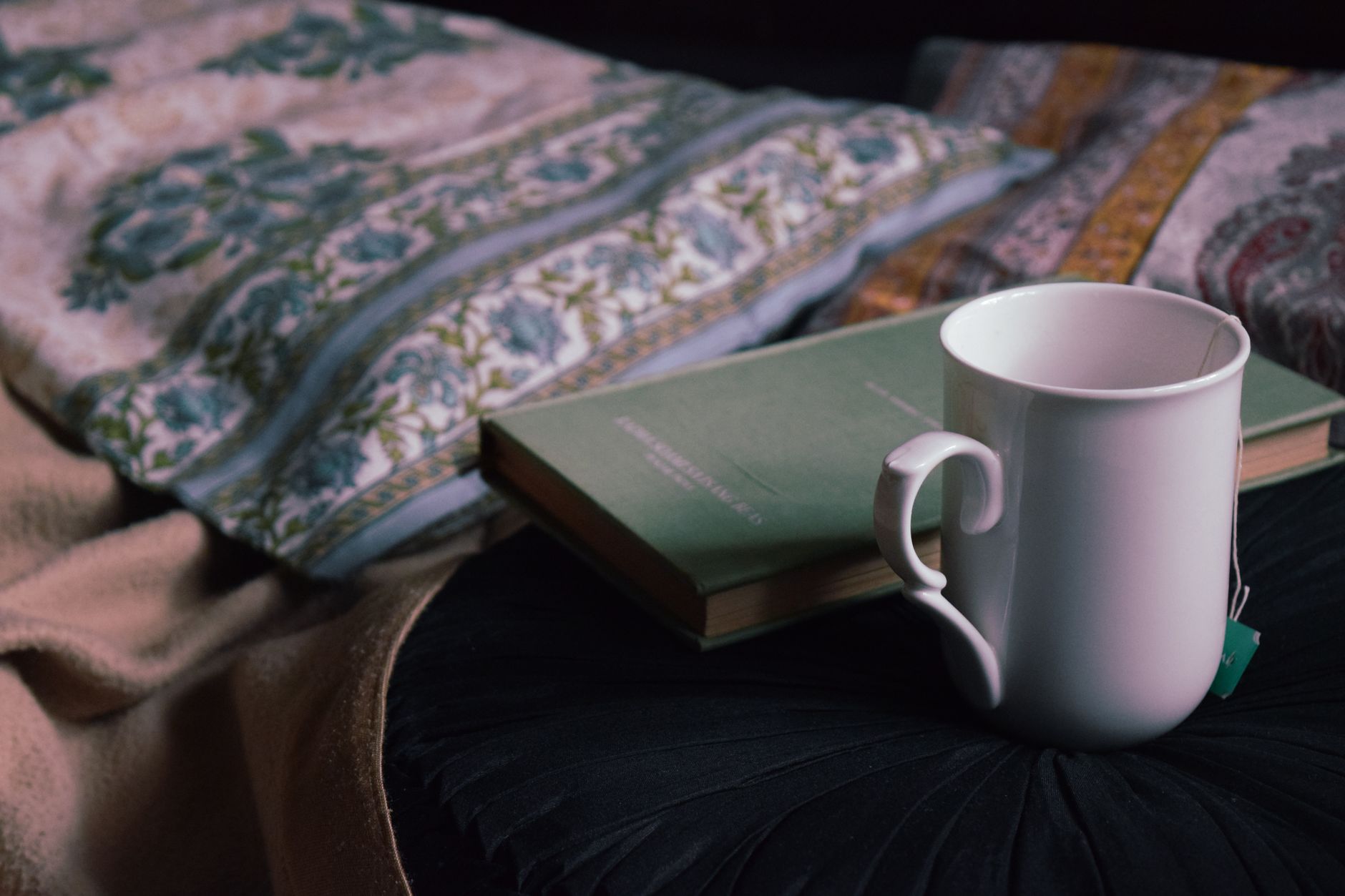 A comforting scene of a pregnant woman reading a book with a cup of herbal tea and a healthy snack like a banana on her bedside table