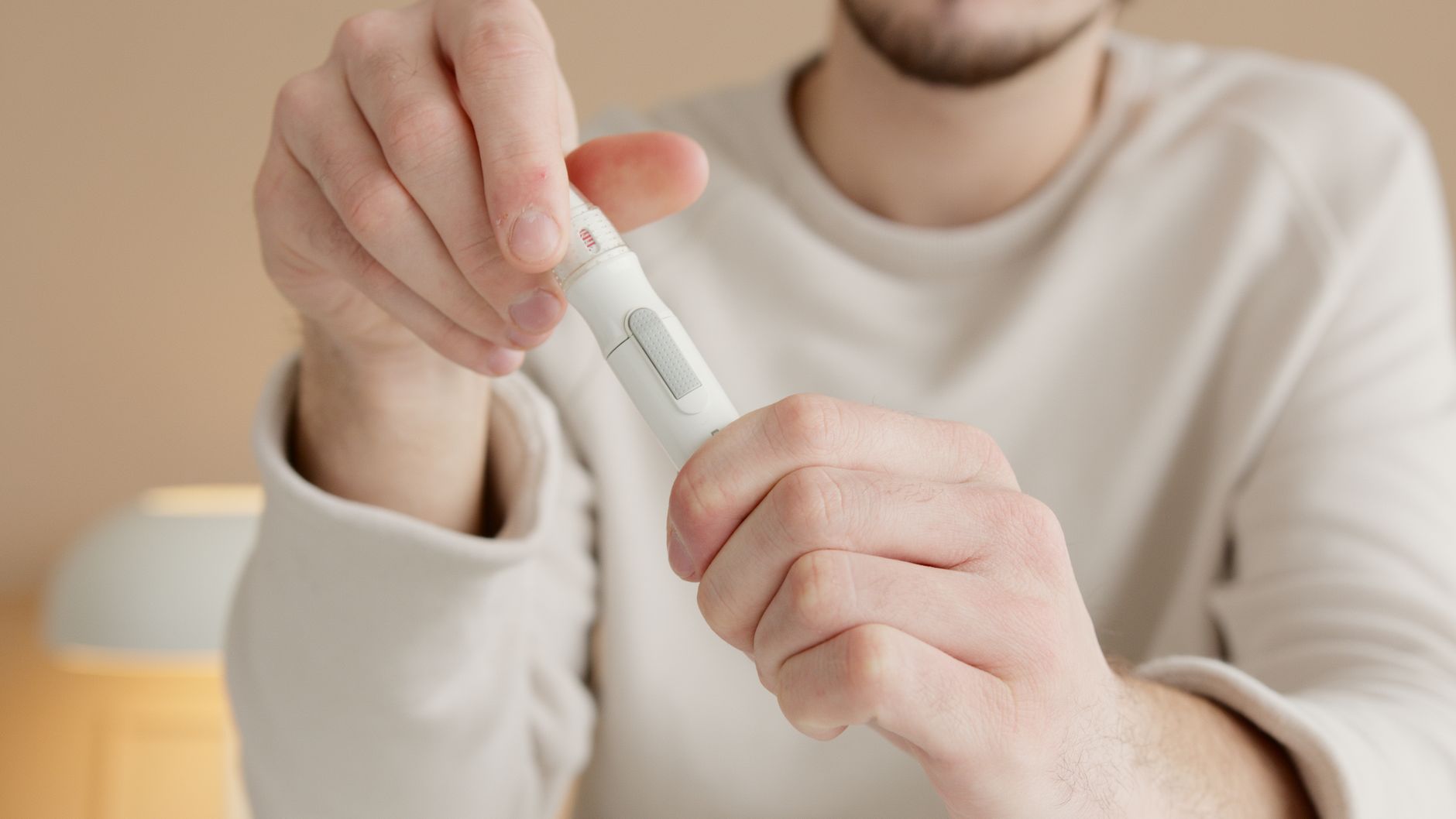 A pregnant woman with gestational diabetes checking her blood sugar levels with a glucose monitor, seated comfortably on a couch