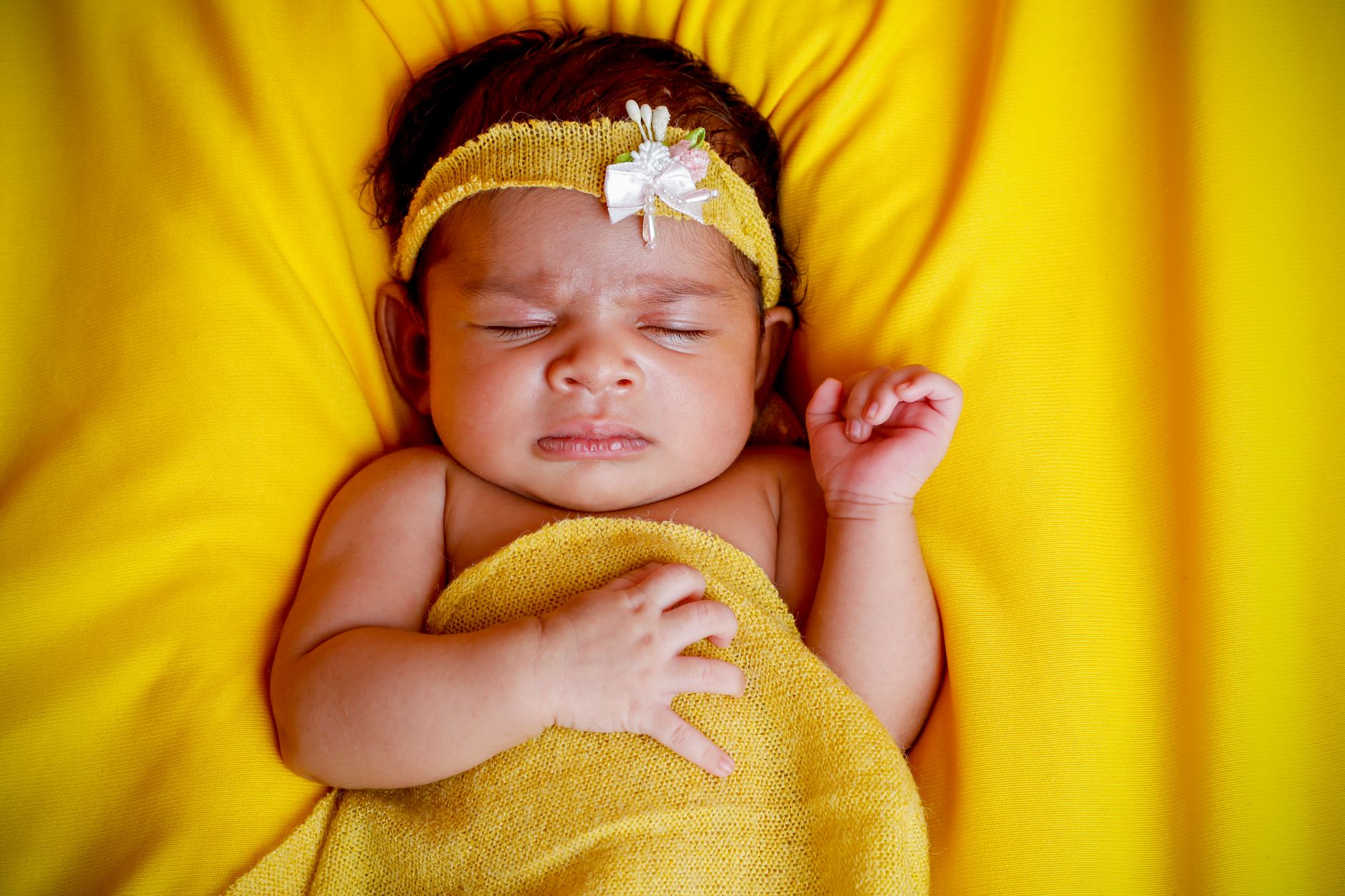 Preterm infant receiving gentle nasal CPAP, soft blanket, dimmed NICU lighting, caregiver gently adjusting tubing