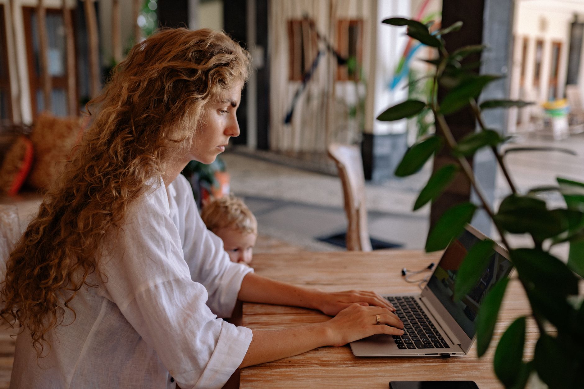 Woman smiling at laptop with child's drawing in background