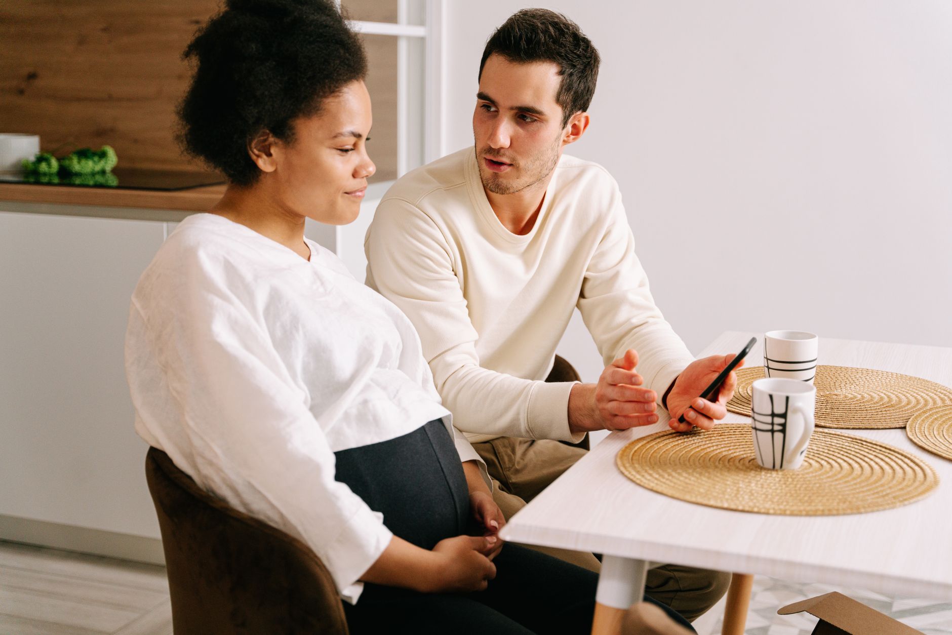 A couple sitting on a couch talking, holding hands