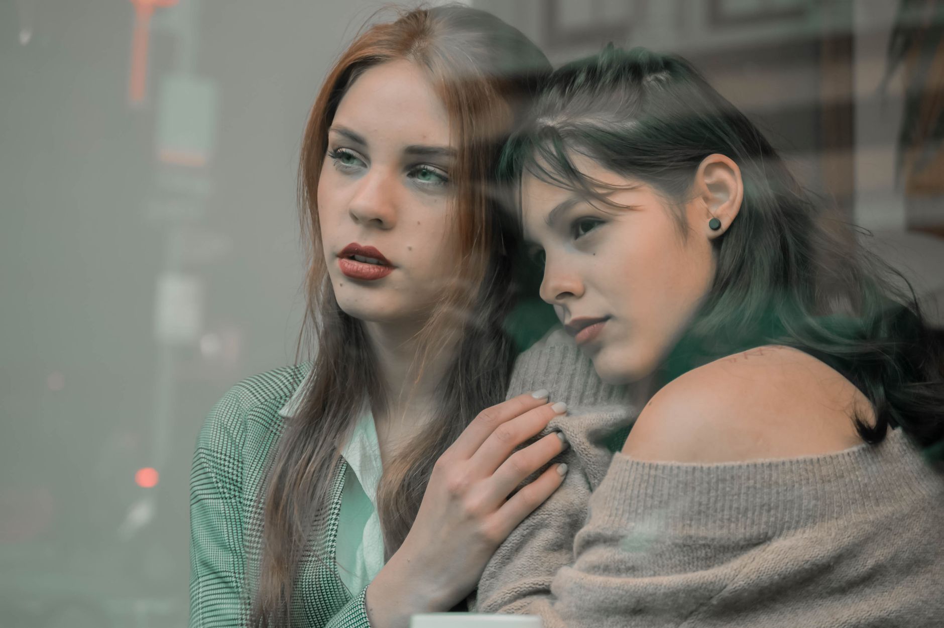 A woman sitting on a couch with a friend, hugging